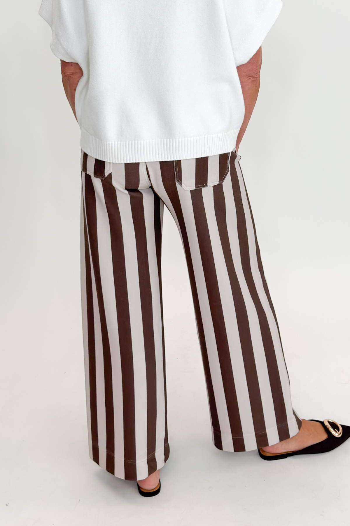 Back view of woman wearing Swagger Boutique’s sweater with Brown & Beige Striped Pants by Entro against white studio background.