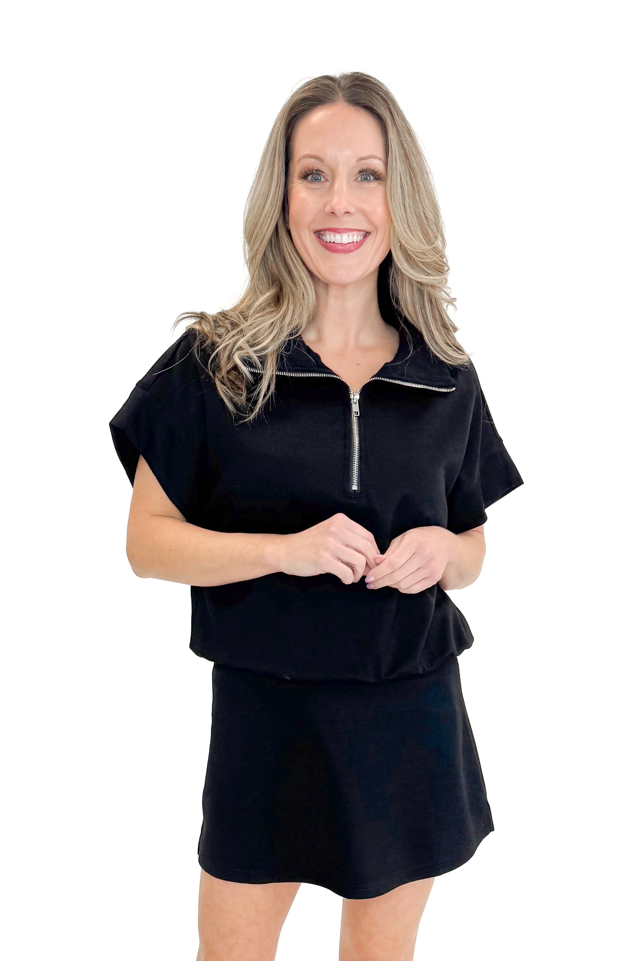 Front view of woman wearing Black Athleisure Skirt with matching sweatshirt against white studio background.