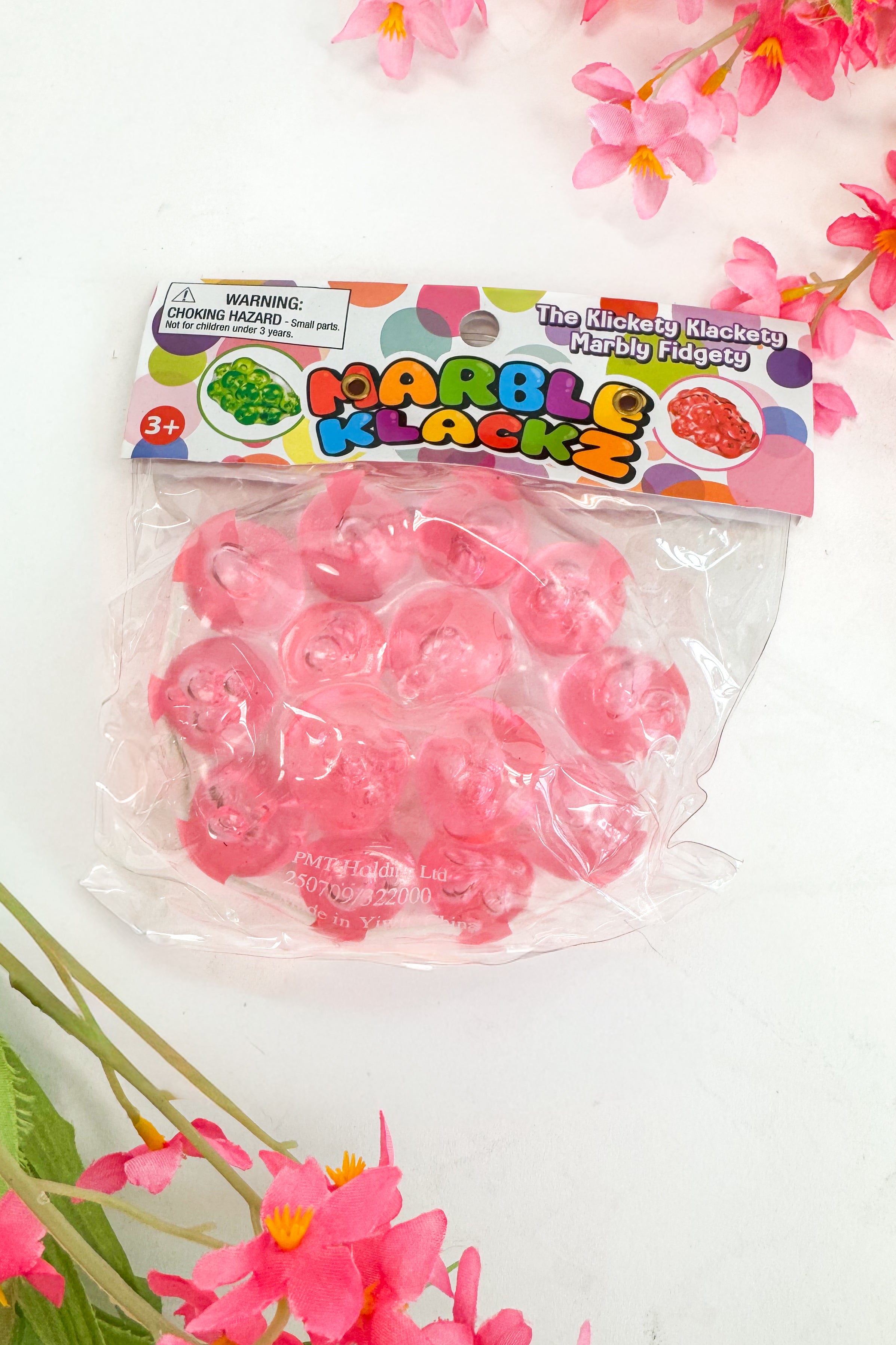 Packaged pink fidget toys with colorful label on a white background with pink flowers.