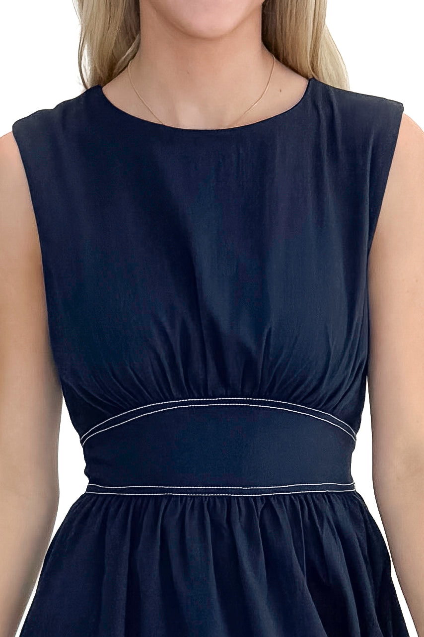 Front detail view of woman wearing Navy Stitch Waist Mid Dress against white studio background.