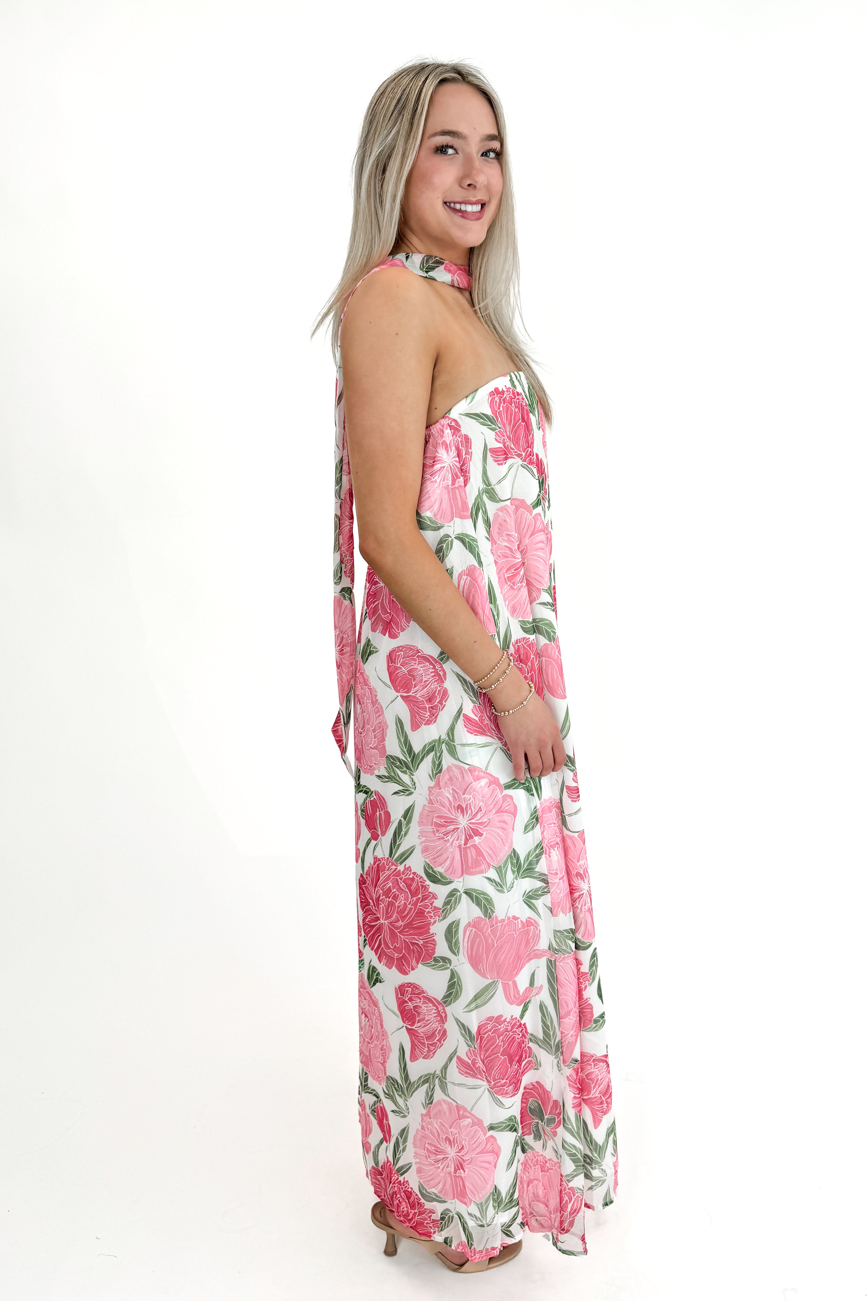 Side view of woman wearing Pink Floral Maxi Dress With Convertible Scarf against white studio background.