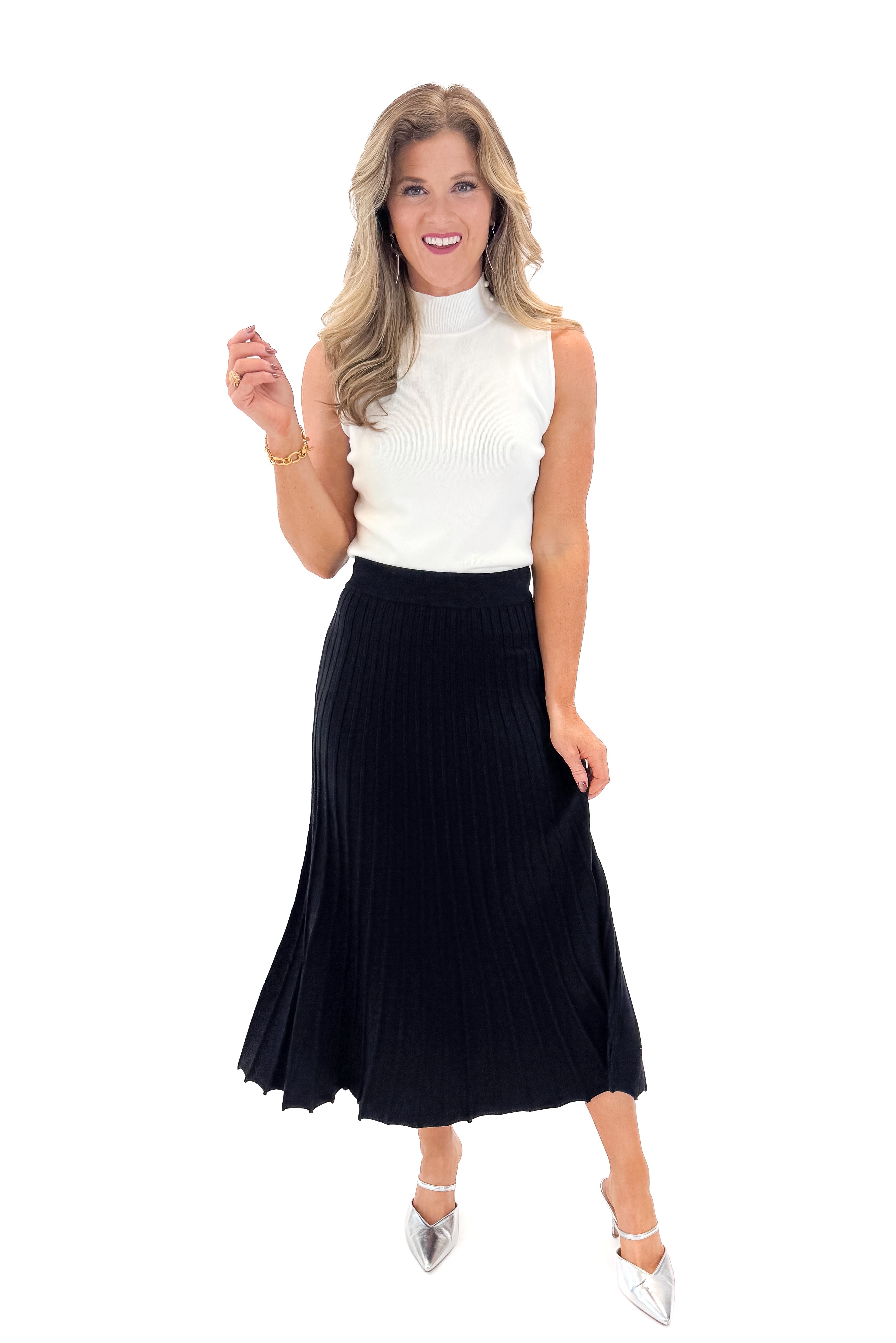 Front view of woman wearing Off White Pearl Detail Mock Neck Top with Black Pleated Sweater Skirt against white studio background.