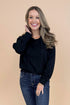 Woman wearing Black Hooded Sweatshirt and jeans with a tan background.