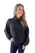Front view of woman wearing charcoal sweater with jeans against white studio background.