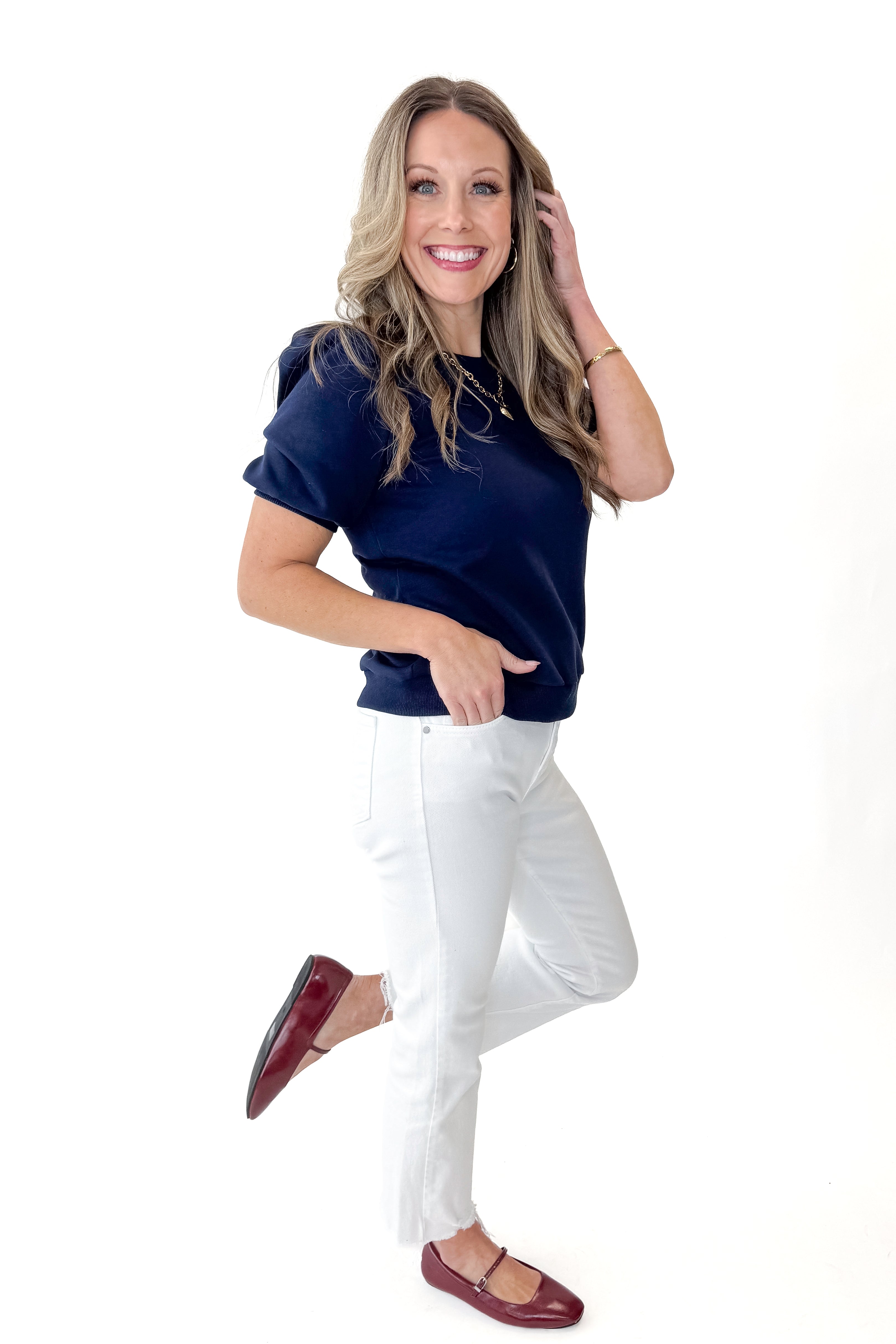 Side view of woman wearing Navy Short Sleeve Sweatshirt with jeans against white studio background.