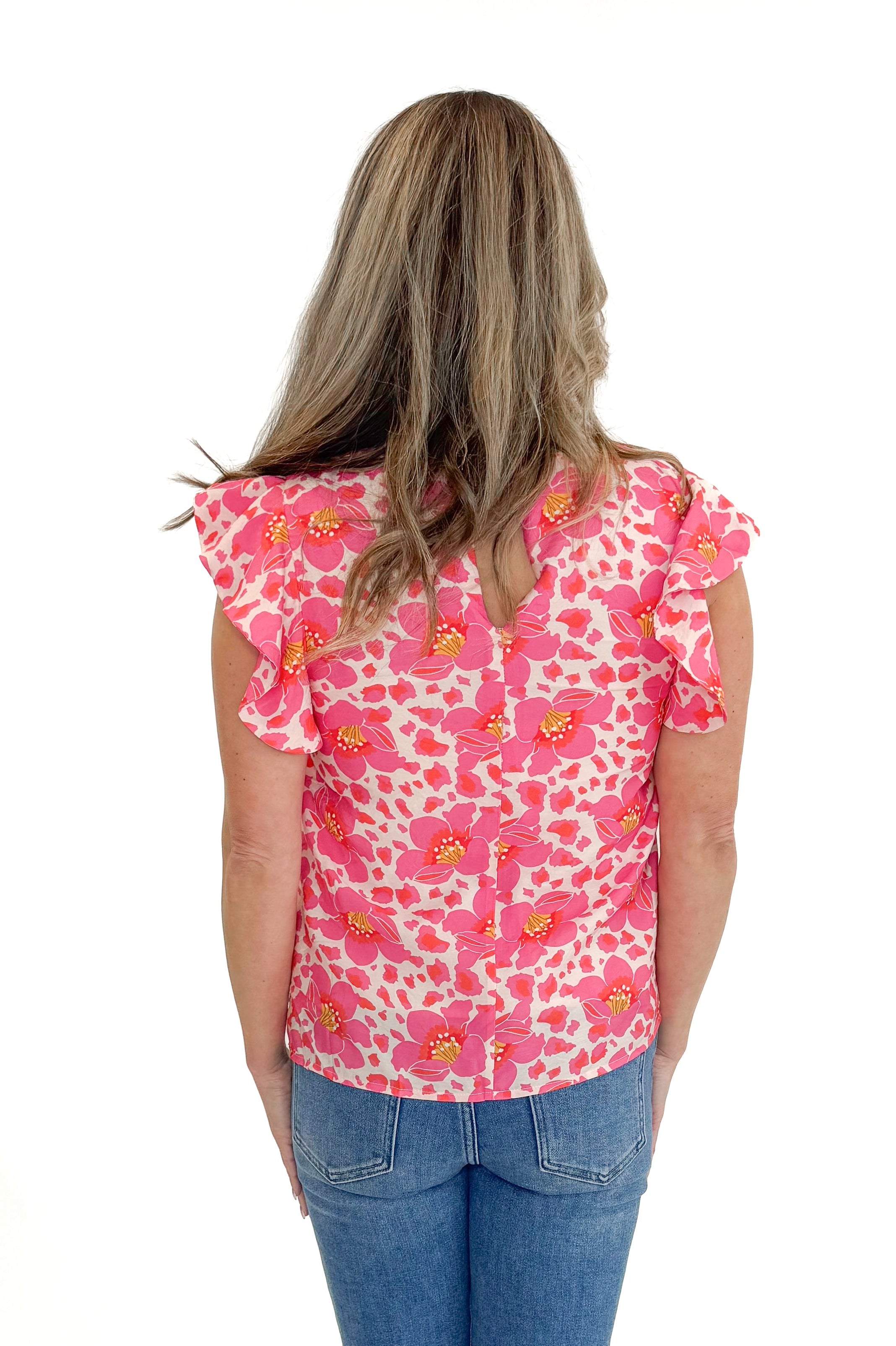 Back view of woman wearing Pink Floral Printed Ruffle Sleeve Top with jeans against white studio background.
