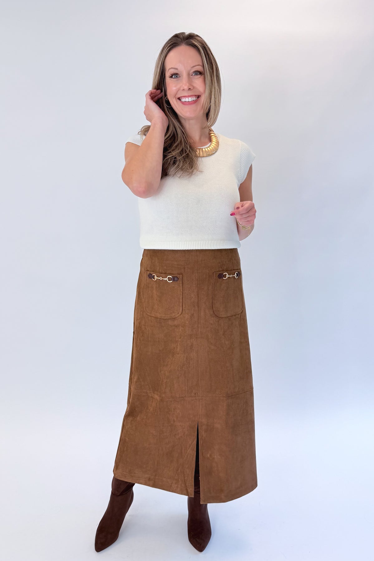 Front view of woman wearing Swagger Boutique’s White Cap Sleeve Sweater by PINCH with Camel Suede Midi Skirt With Pockets by Entro against white studio background.