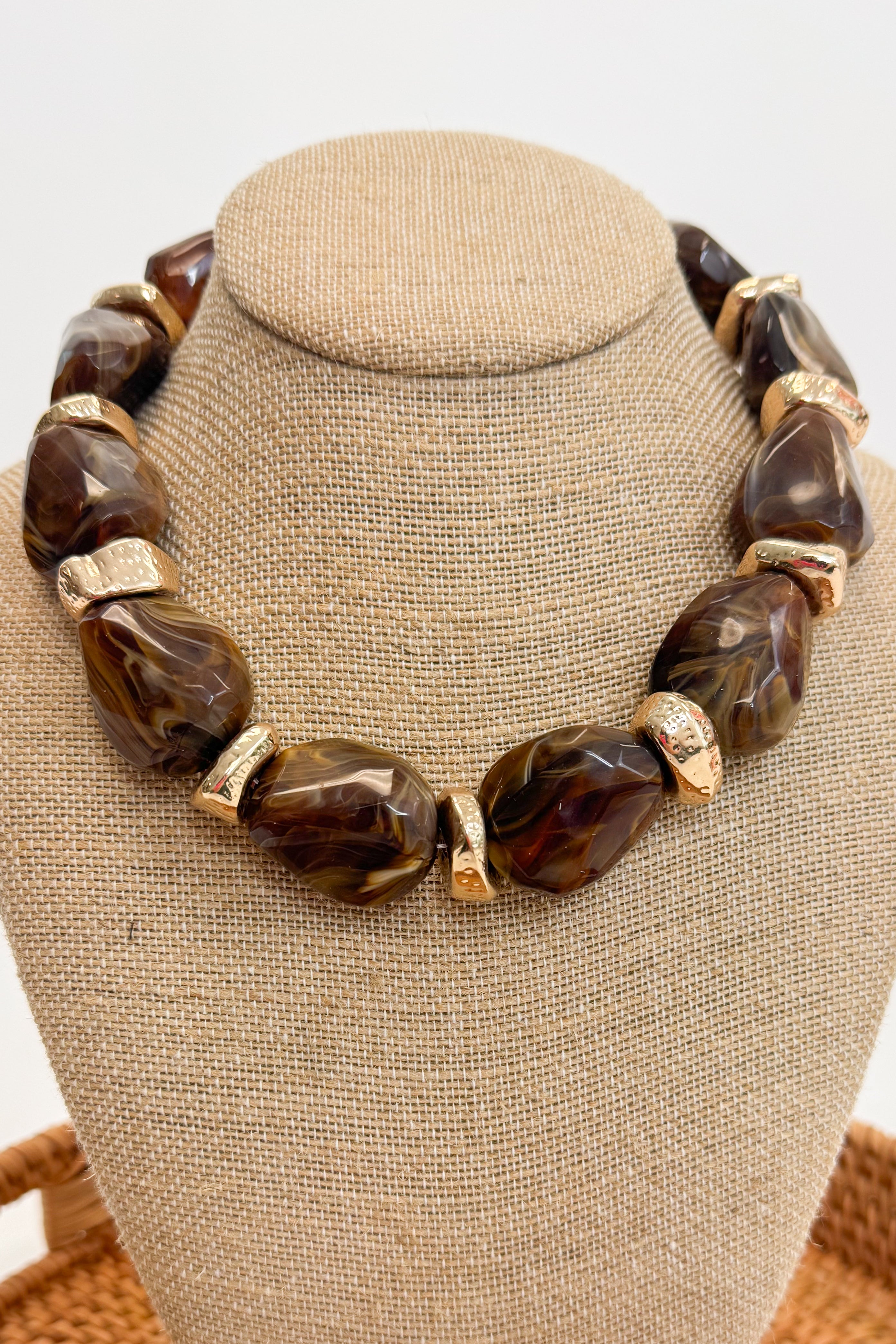 Chunky Brown Beaded Necklace with Gold Accents on a beige bust
