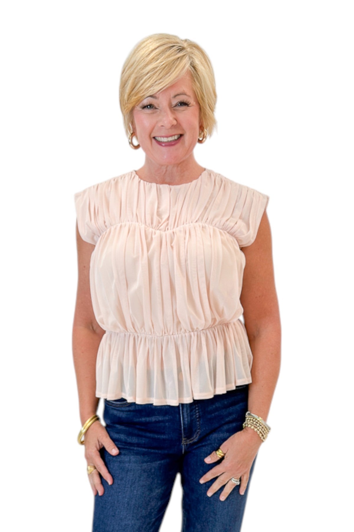 Front view of woman wearing Swagger Boutique’s Champagne Shirred Peplum Top with jeans against white studio background.