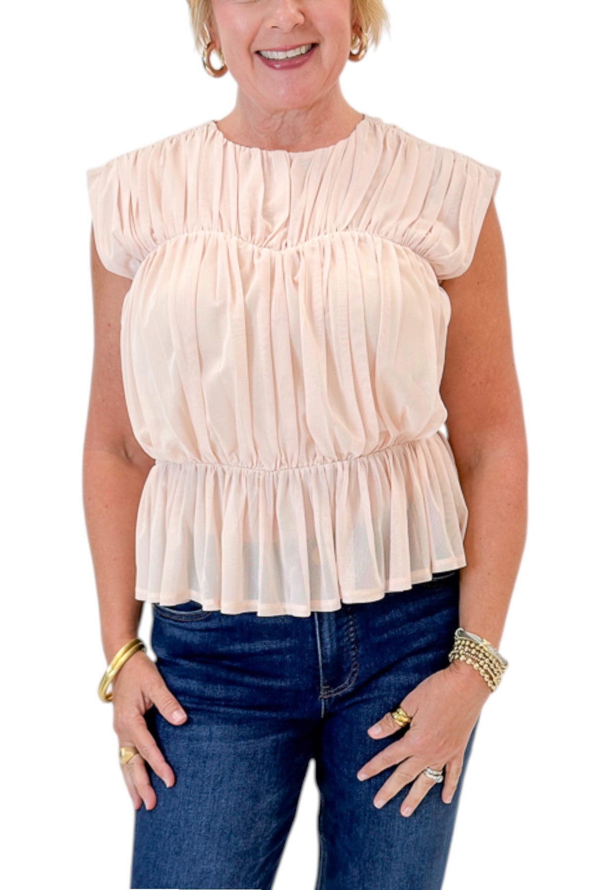 Front detail view of woman wearing Swagger Boutique’s Champagne Shirred Peplum Top with jeans against white studio background.