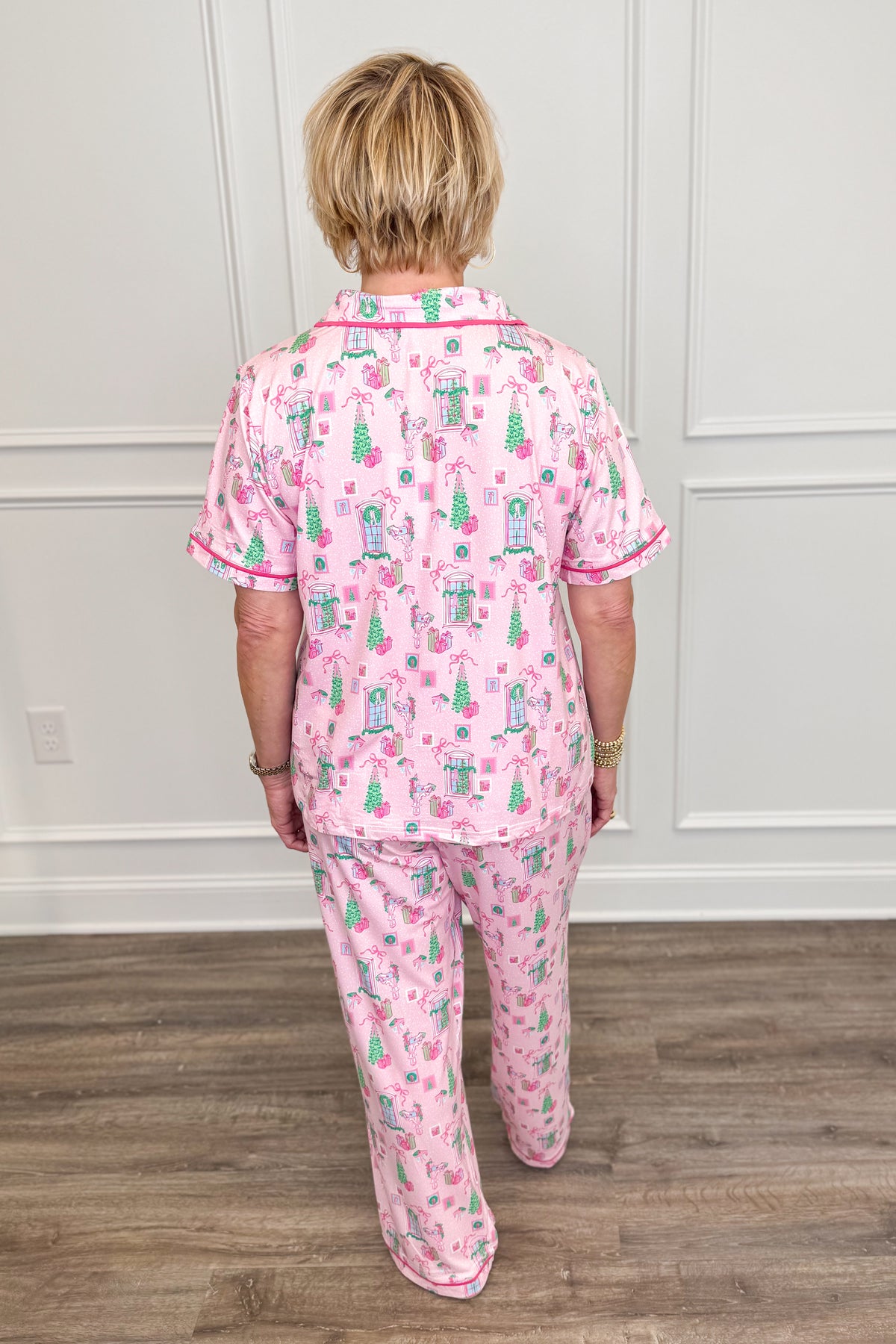 Back view of the Christmas Cottage Charlotte Pajama Set, showcasing the allover pink, green, and festive holiday print. The short-sleeve pajama top has a relaxed fit, paired with matching straight-leg pants.