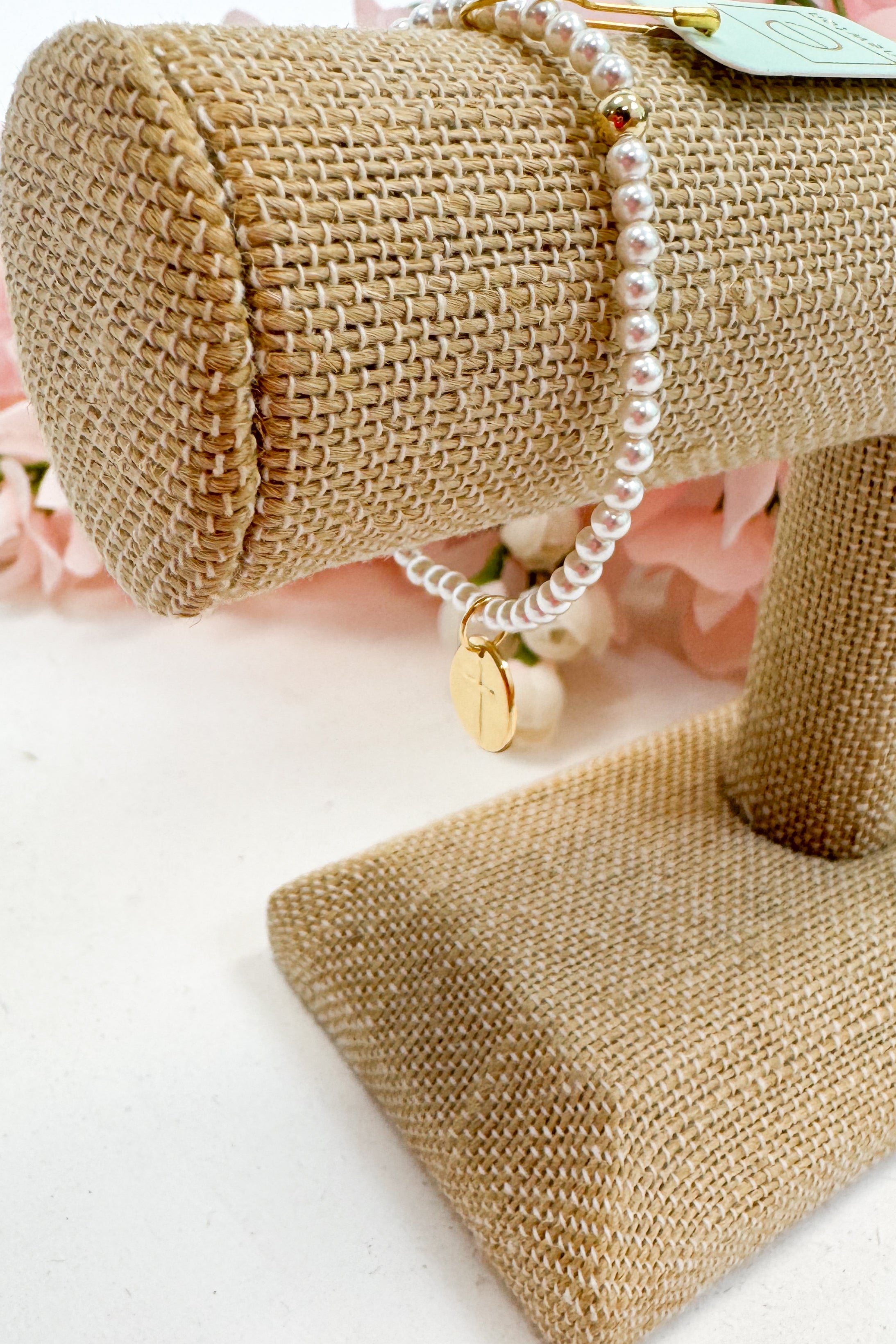 Pearl bracelet on a burlap roll with a pink floral background