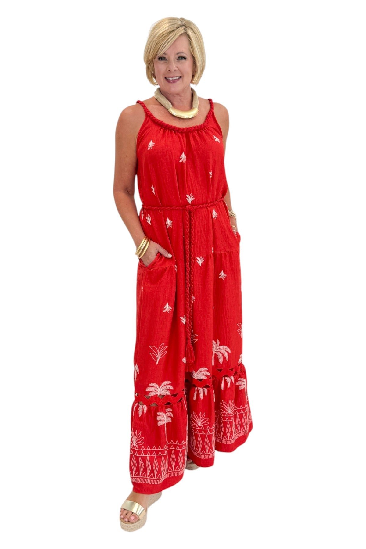 Front view of woman wearing Swagger Boutiqueās Coral Palm Embroidered Maxi Dress with sandals against white studio background.