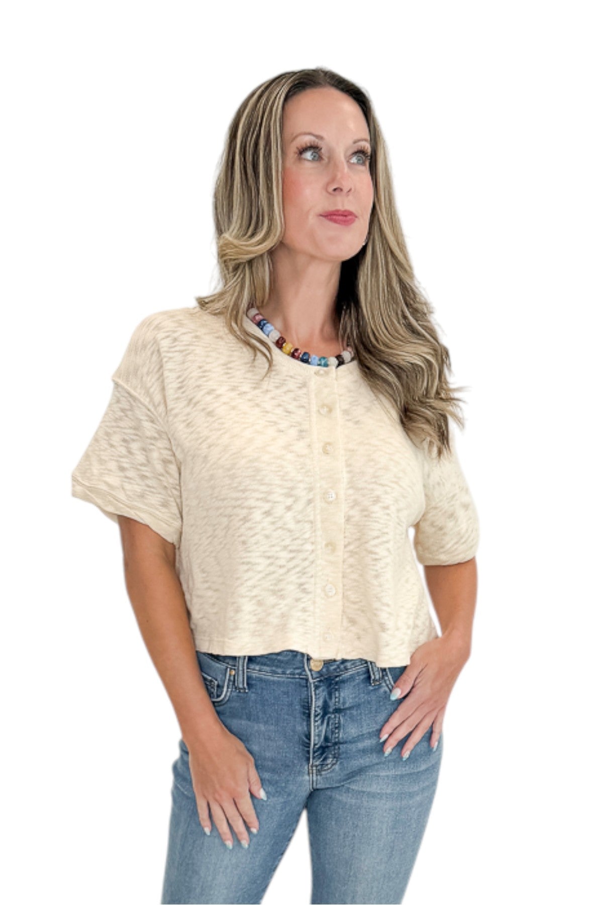 Front view of woman wearing Swagger Boutiqueās Cream Button Up Short Sleeve Sweater with jeans against white studio background.