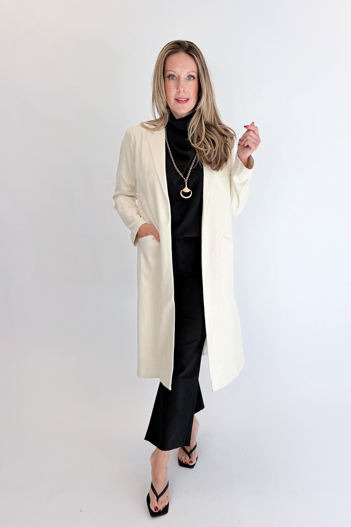 Front view of woman wearing Swagger Boutique’s Cream Suede Duster Cardigan with jeans against white studio background.