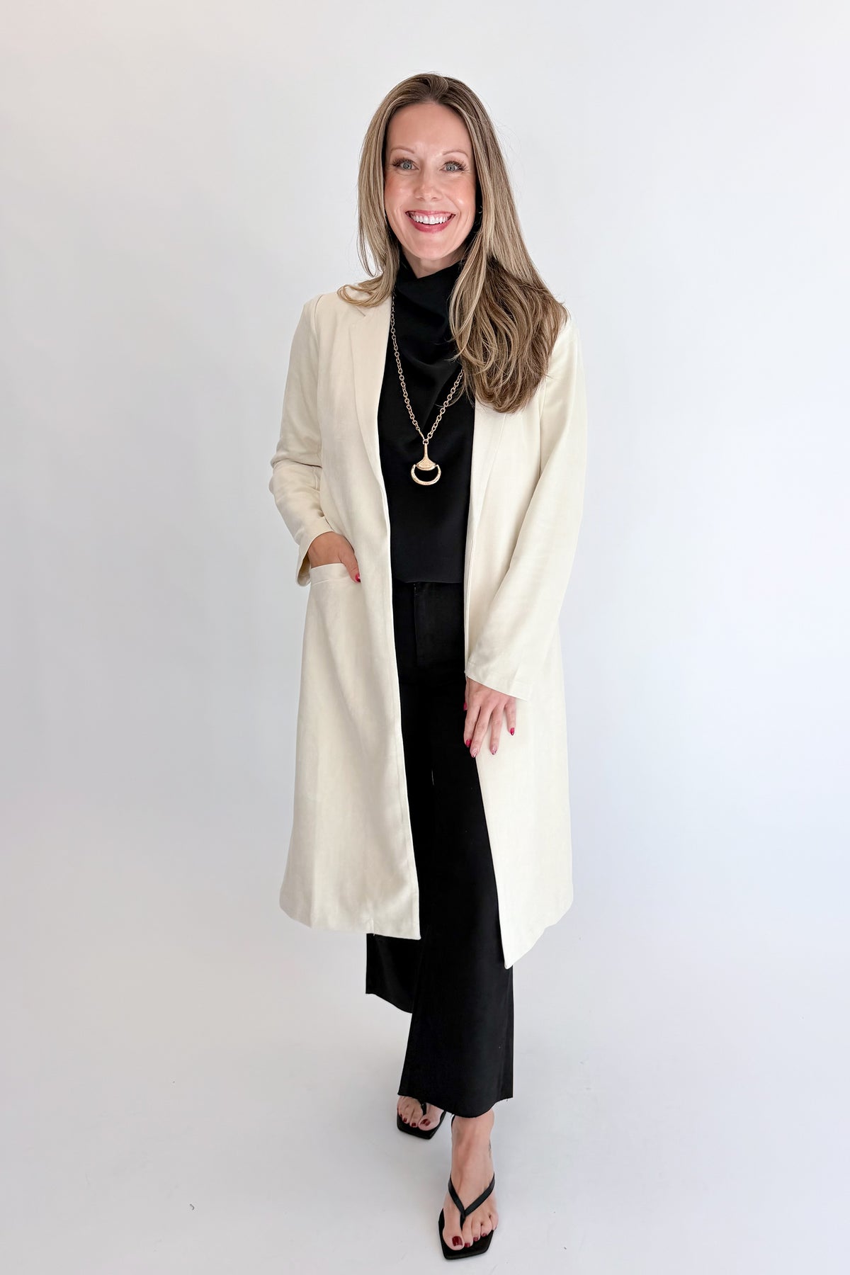 Front view of woman wearing Swagger Boutique’s Cream Suede Duster Cardigan with jeans against white studio background.