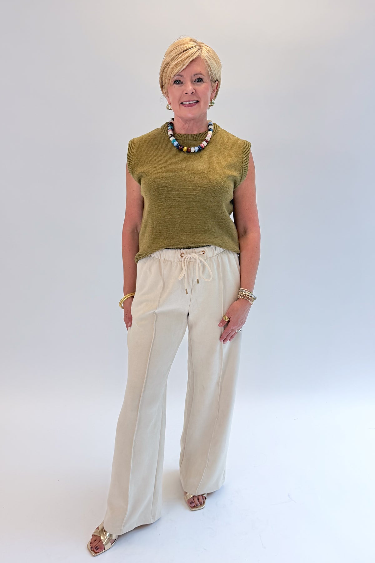 Front view of woman wearing Swagger Boutique’s Cream Suede Pants with sweater against white studio background.