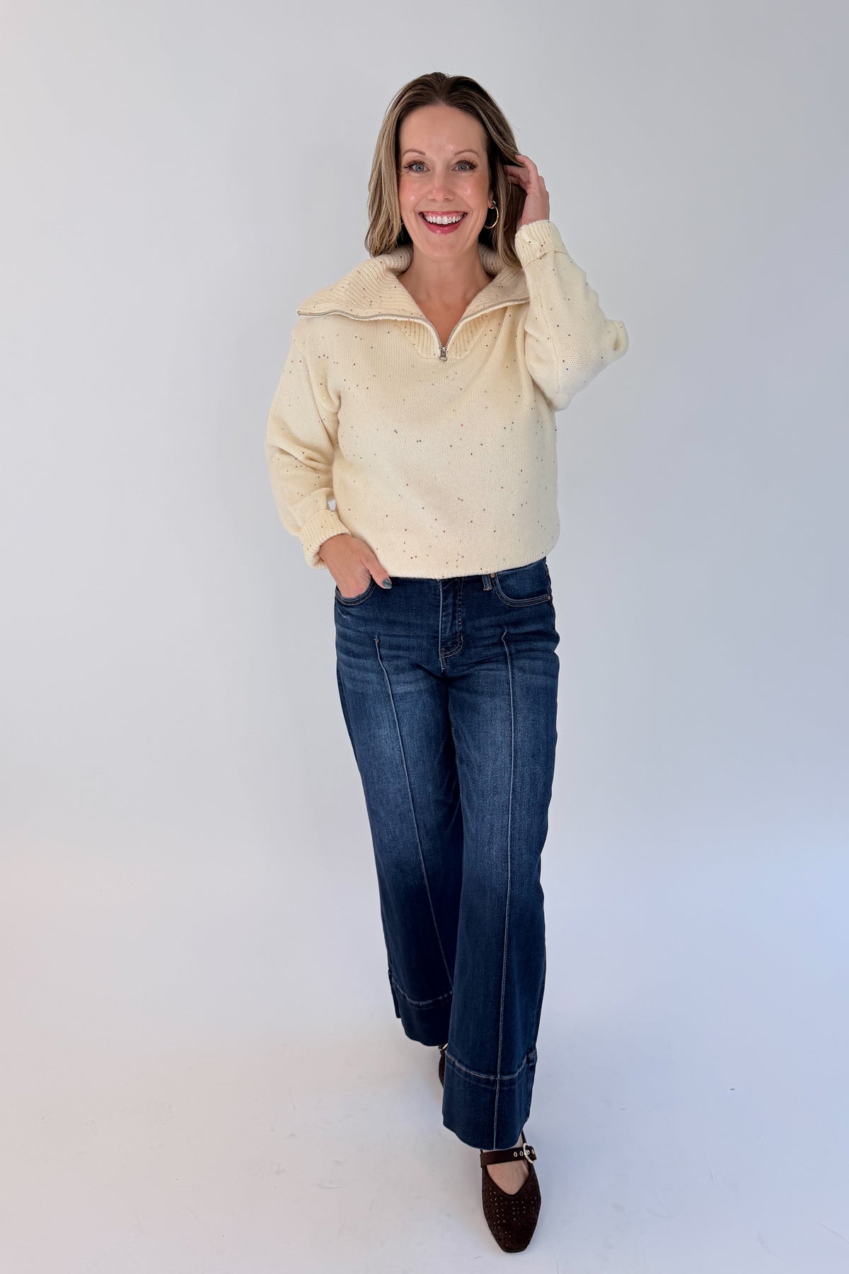Front view of woman wearing Swagger Boutique’s Cream With Multi Sequins Sweater with jeans against white studio background.