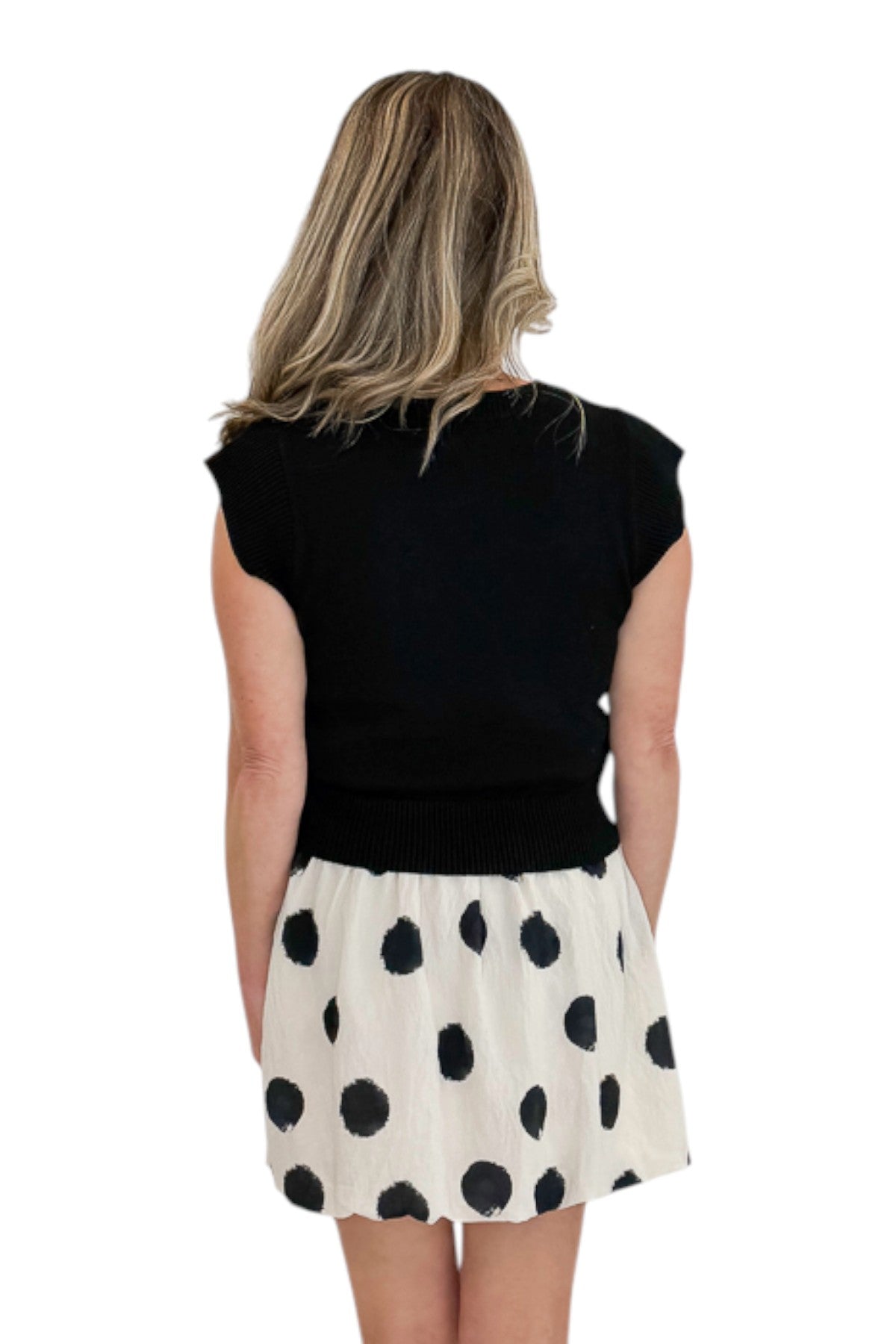 Back view of woman wearing Swagger Boutiqueās Cream & Black Polka Dot Skirt by THML with black sweater against white studio background.