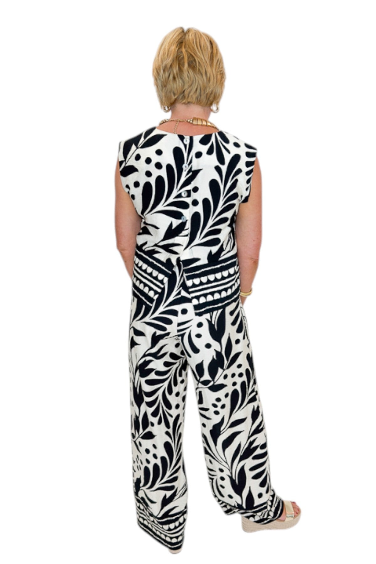 Back view of woman wearing Swagger Boutiqueβs Cream & Black Printed Tank & Wide Leg Pants against white studio background.