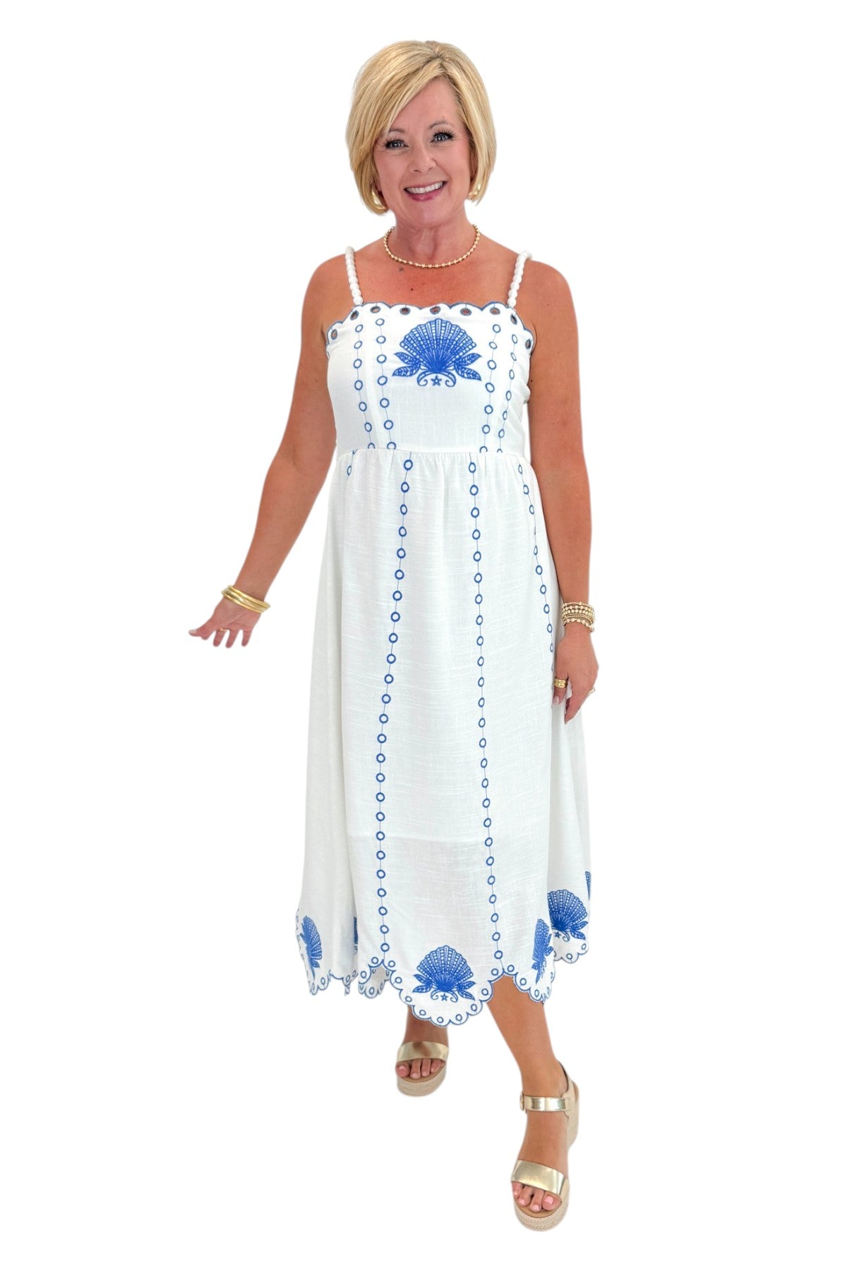 Front view of woman wearing Swagger Boutiqueโs Cream & Blue Shell Embroidered Midi Dress with sandals against white studio background.