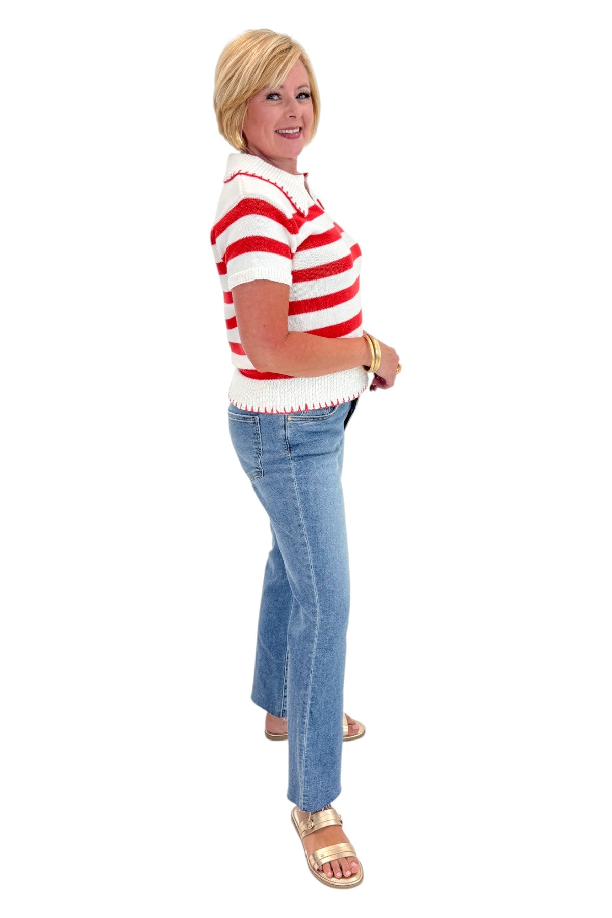 Side view of woman wearing Swagger Boutiqueβs Cream & Coral Striped Knit Top with jeans against white studio background.