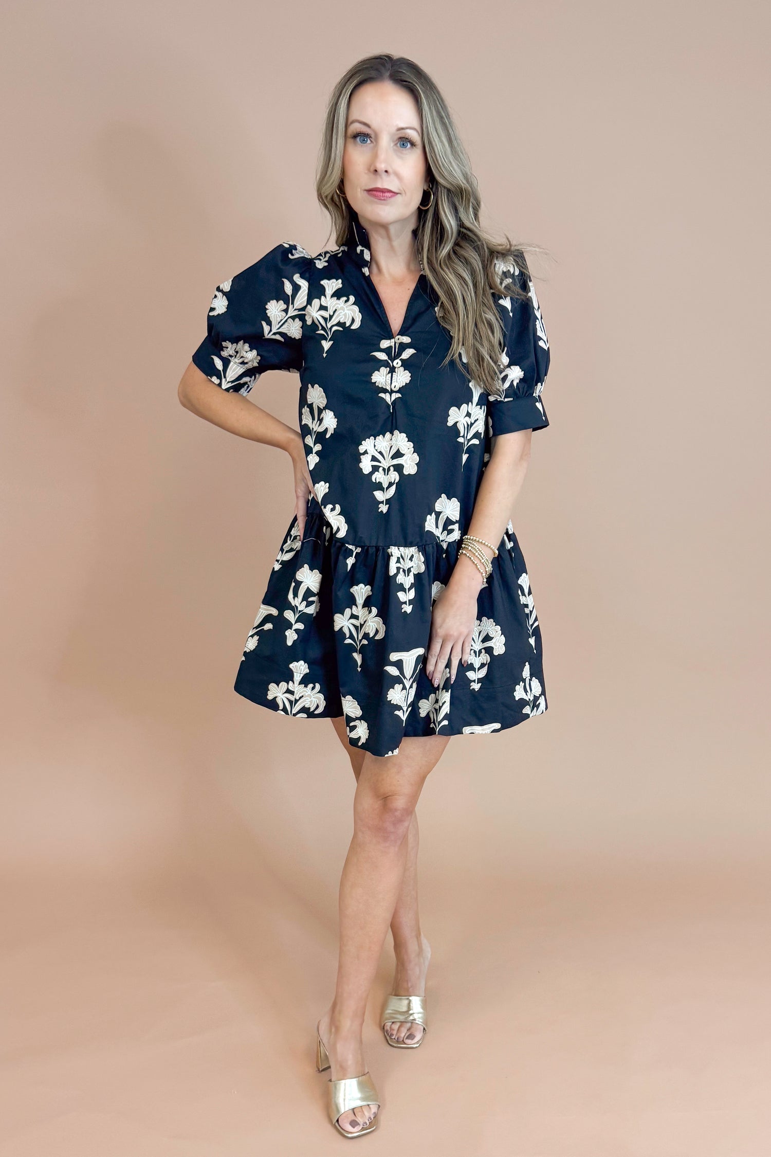 Woman wearing a navy floral dress against a beige background