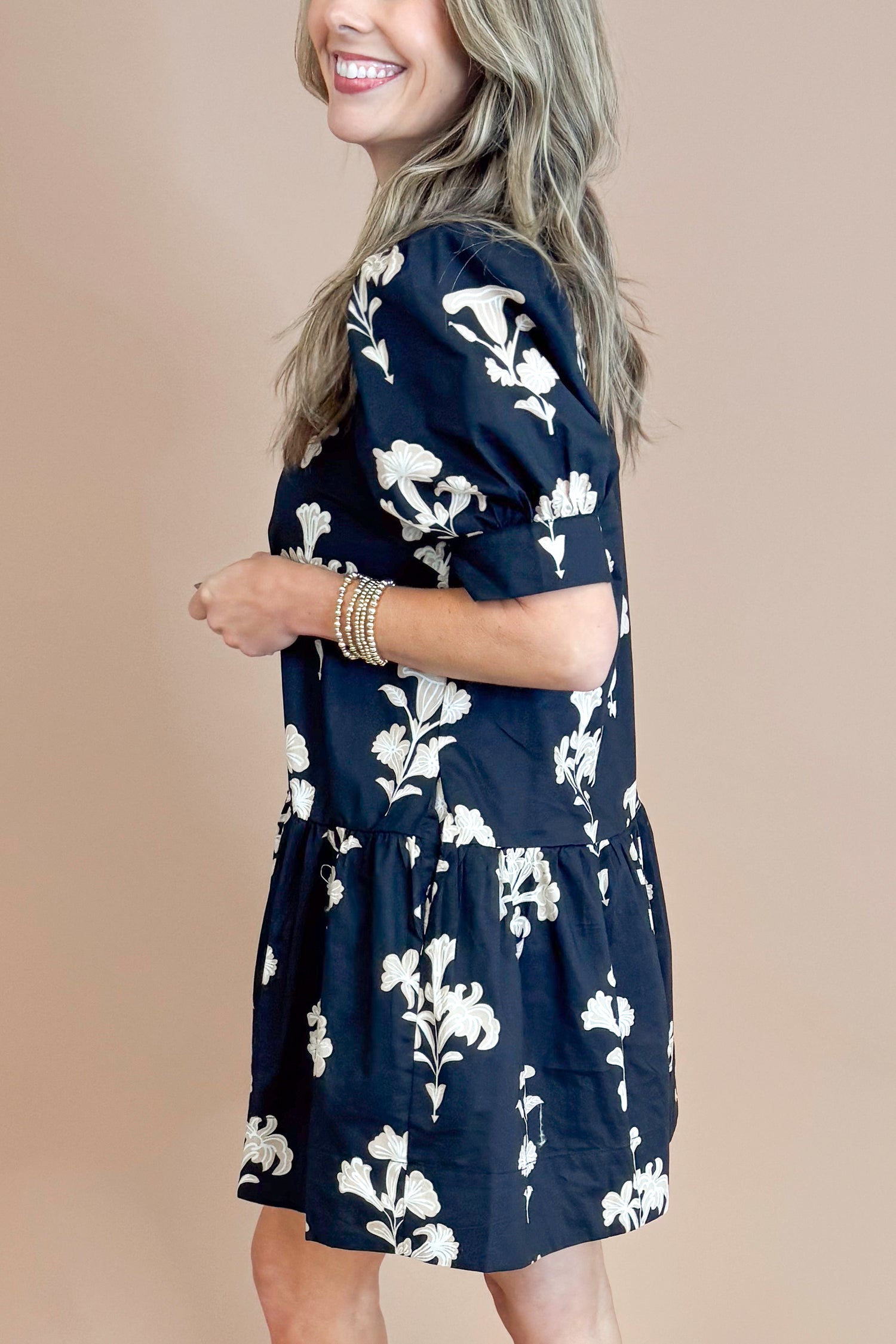 Woman wearing a navy floral dress against a beige background