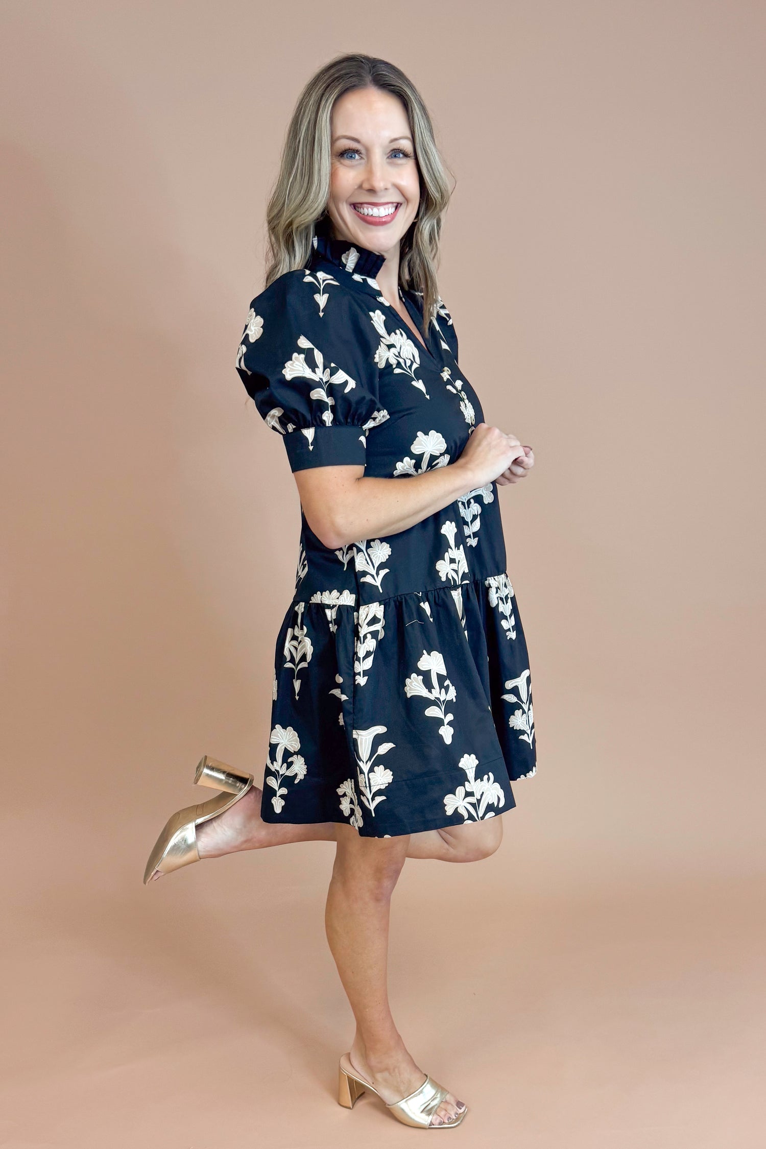 Woman wearing a navy floral dress posing against a beige background
