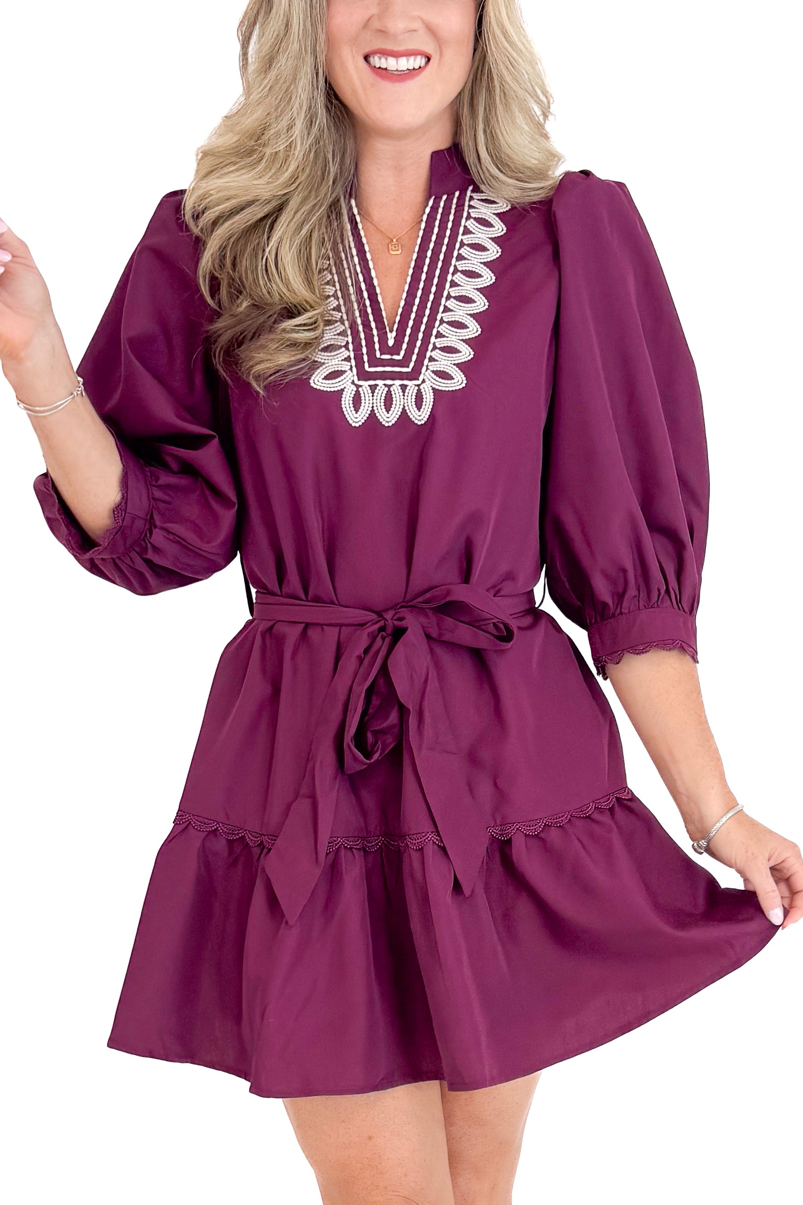 Woman wearing a burgundy dress with lace details on a white background