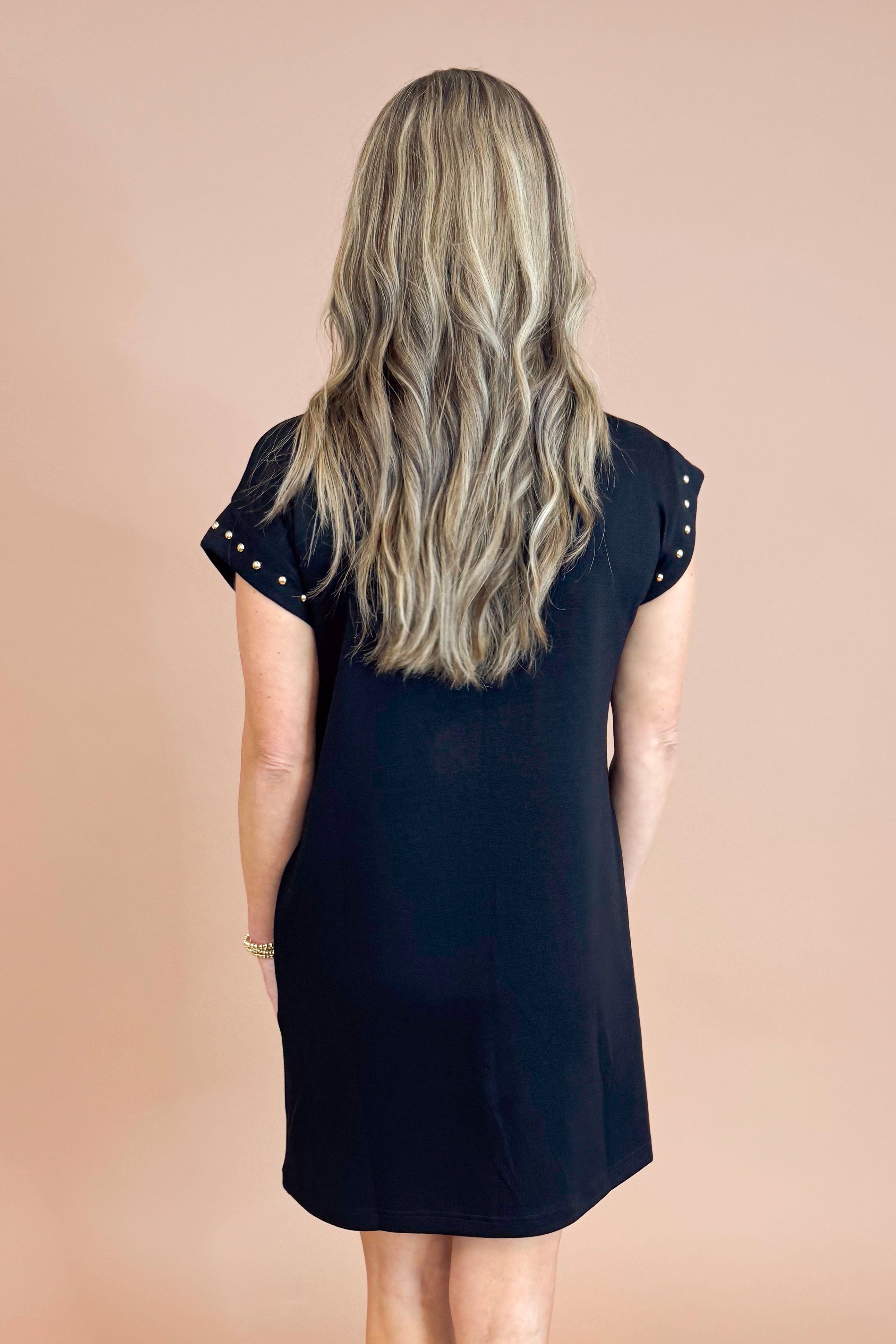 Person wearing a black dress against a beige background