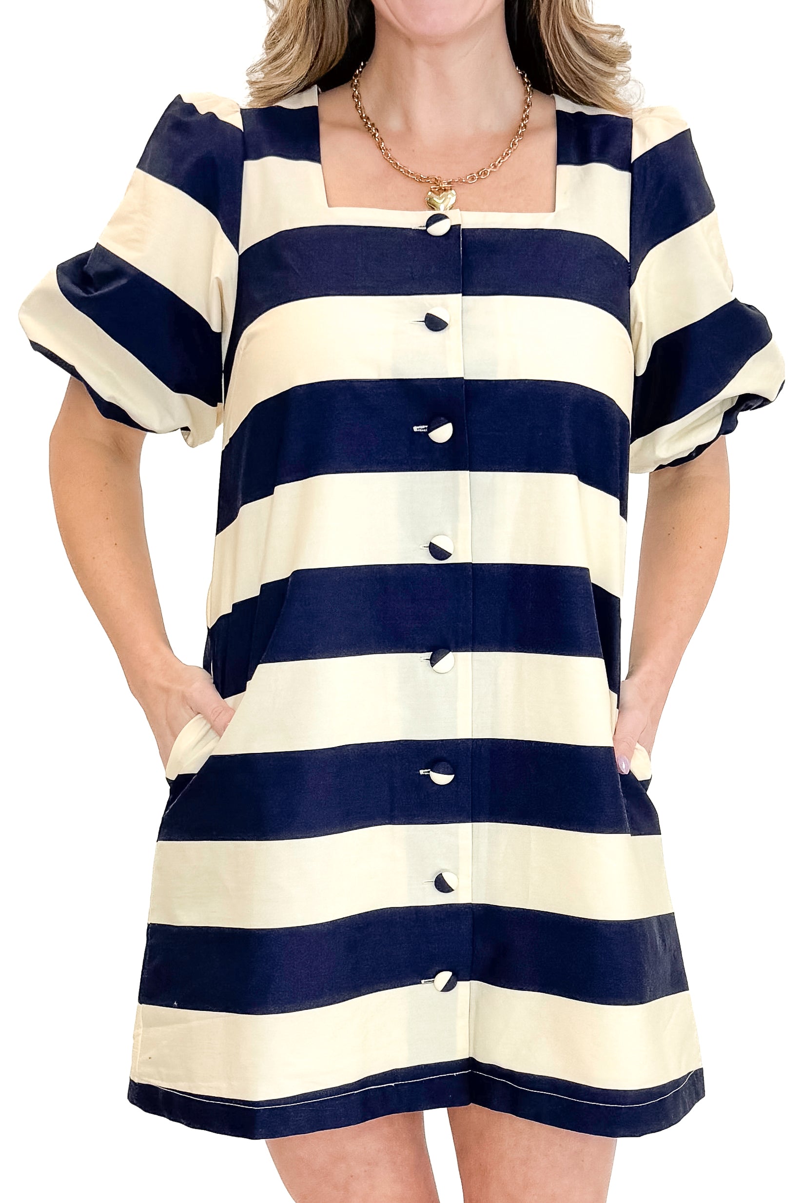 Front detail view of woman wearing Navy & Cream Stripe Button Up Dress by Entro with heels against white studio background.