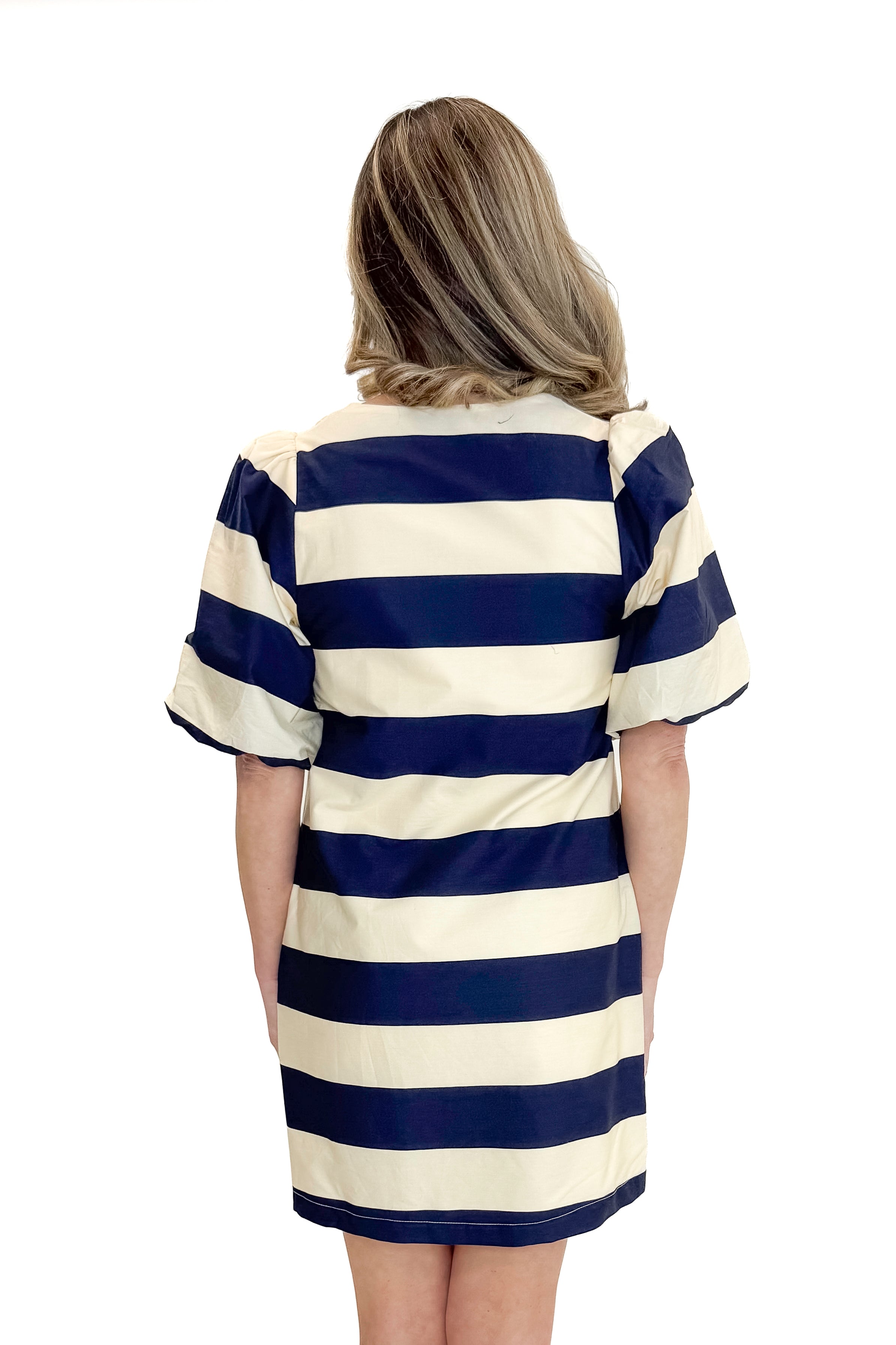 Back view of woman wearing Navy & Cream Stripe Button Up Dress by Entro with heels against white studio background.