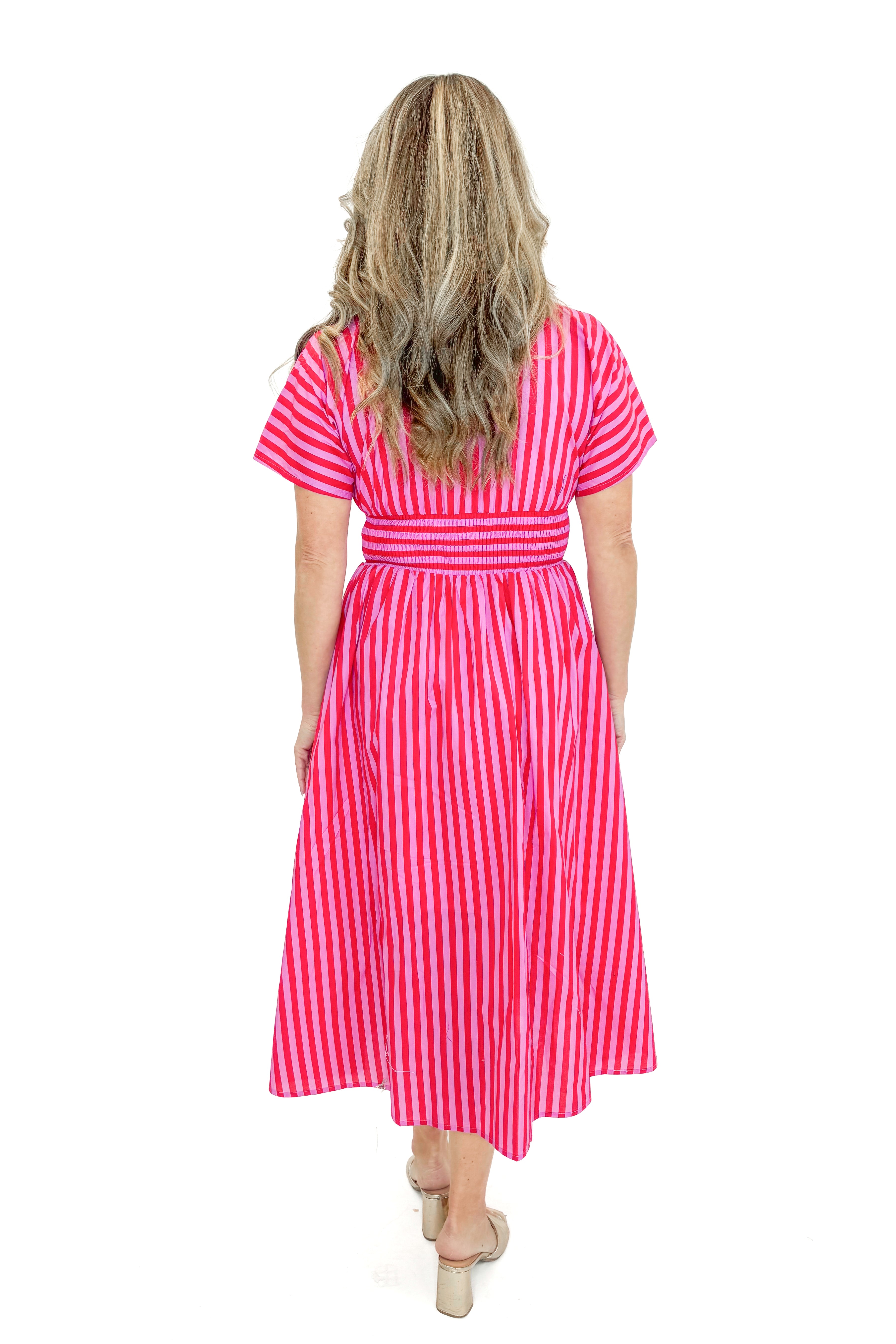 Back view of woman wearing Red & Pink Striped Center Zip Midi Dress by Entro against white studio background.