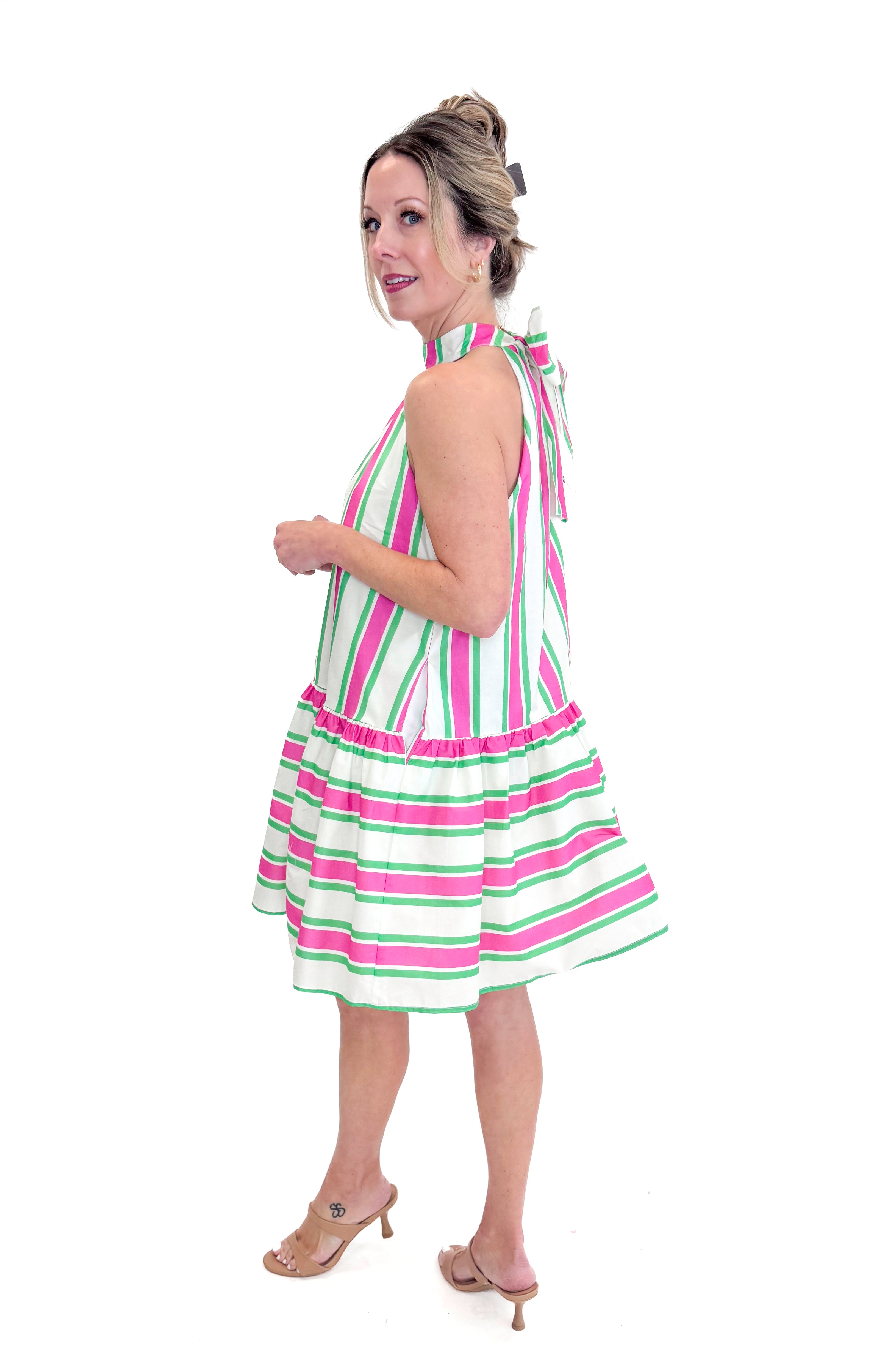 Side view of woman wearing Pink & Green Striped Halter Neck Dress by Entro against white studio background.