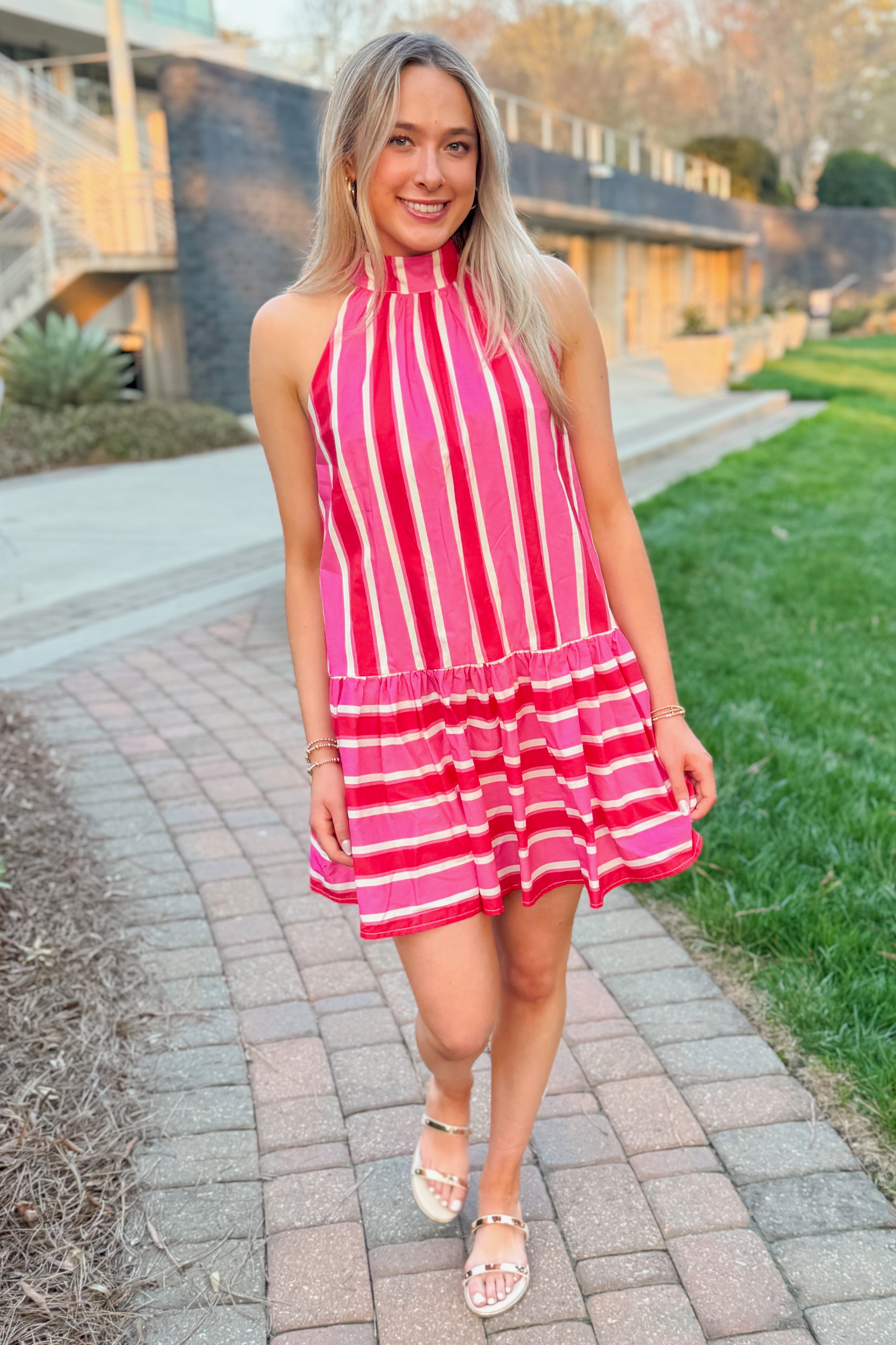 Front view of woman wearing Pink & Red Striped Halter Neck Dress by Entro outside walking.