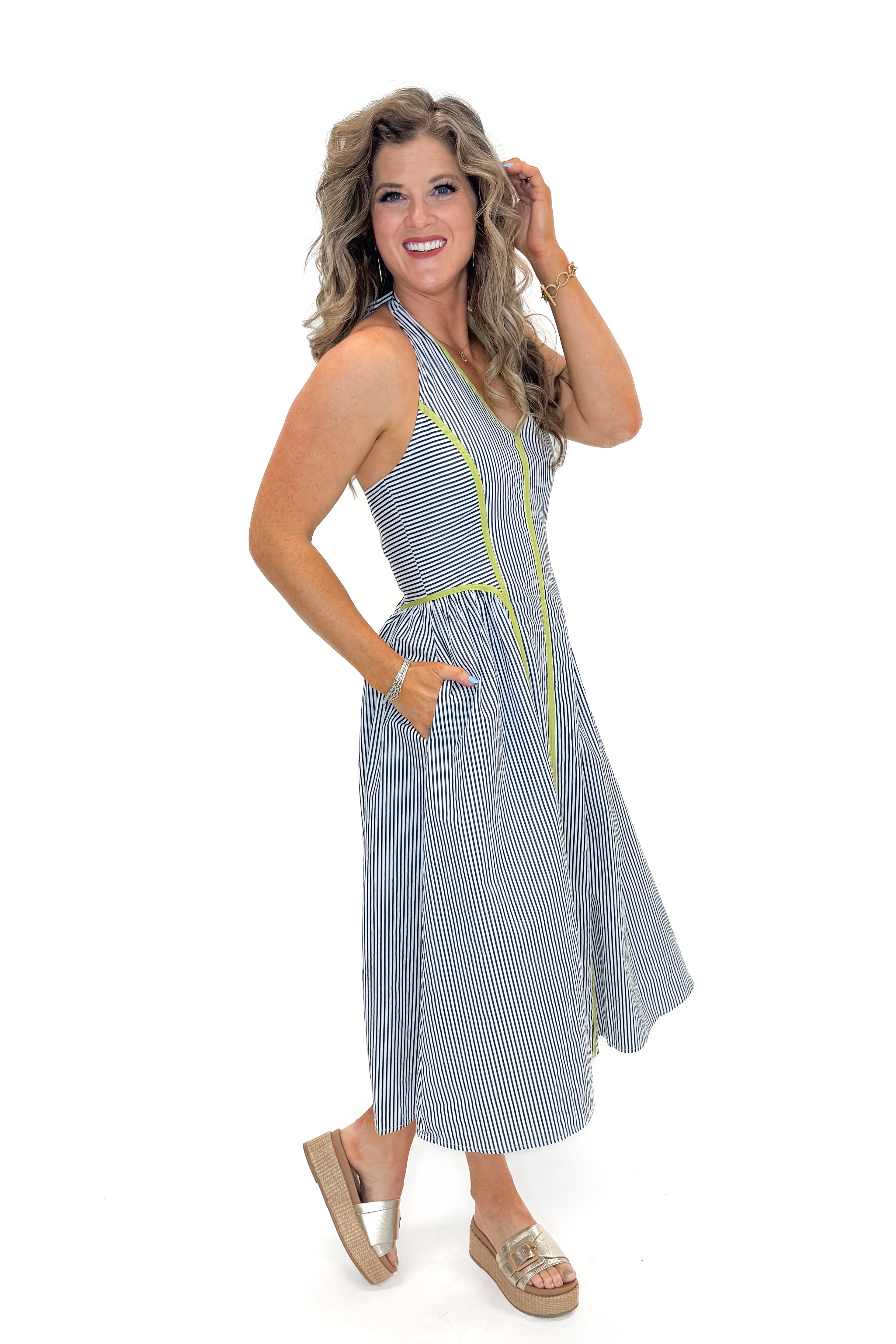 Side view of woman wearing Navy With Green Stripe Detail Halter Midi Dress by Entro with sandals against white studio background.
