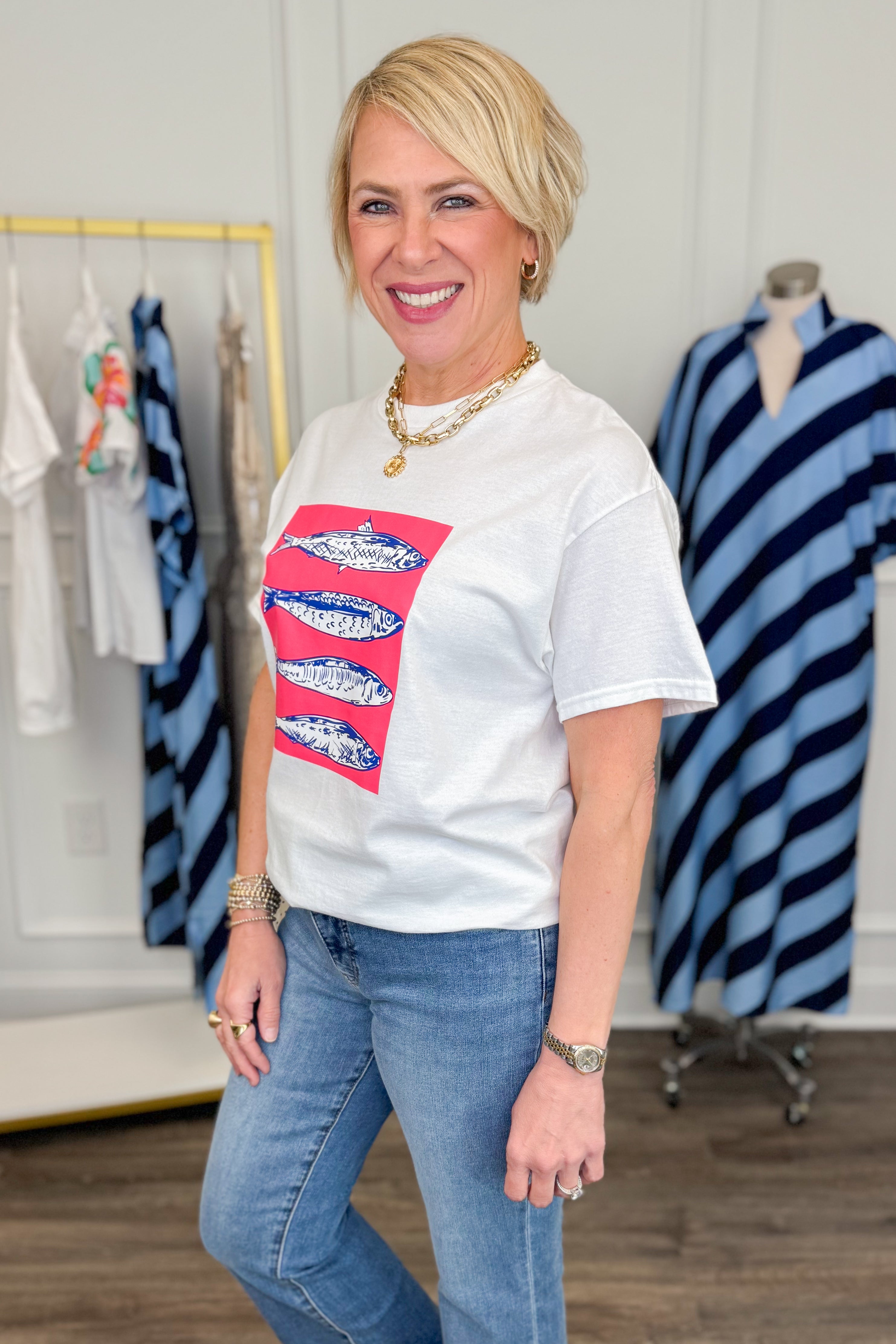 Woman wearing a white t-shirt with a colorful graphic design in a clothing store.
