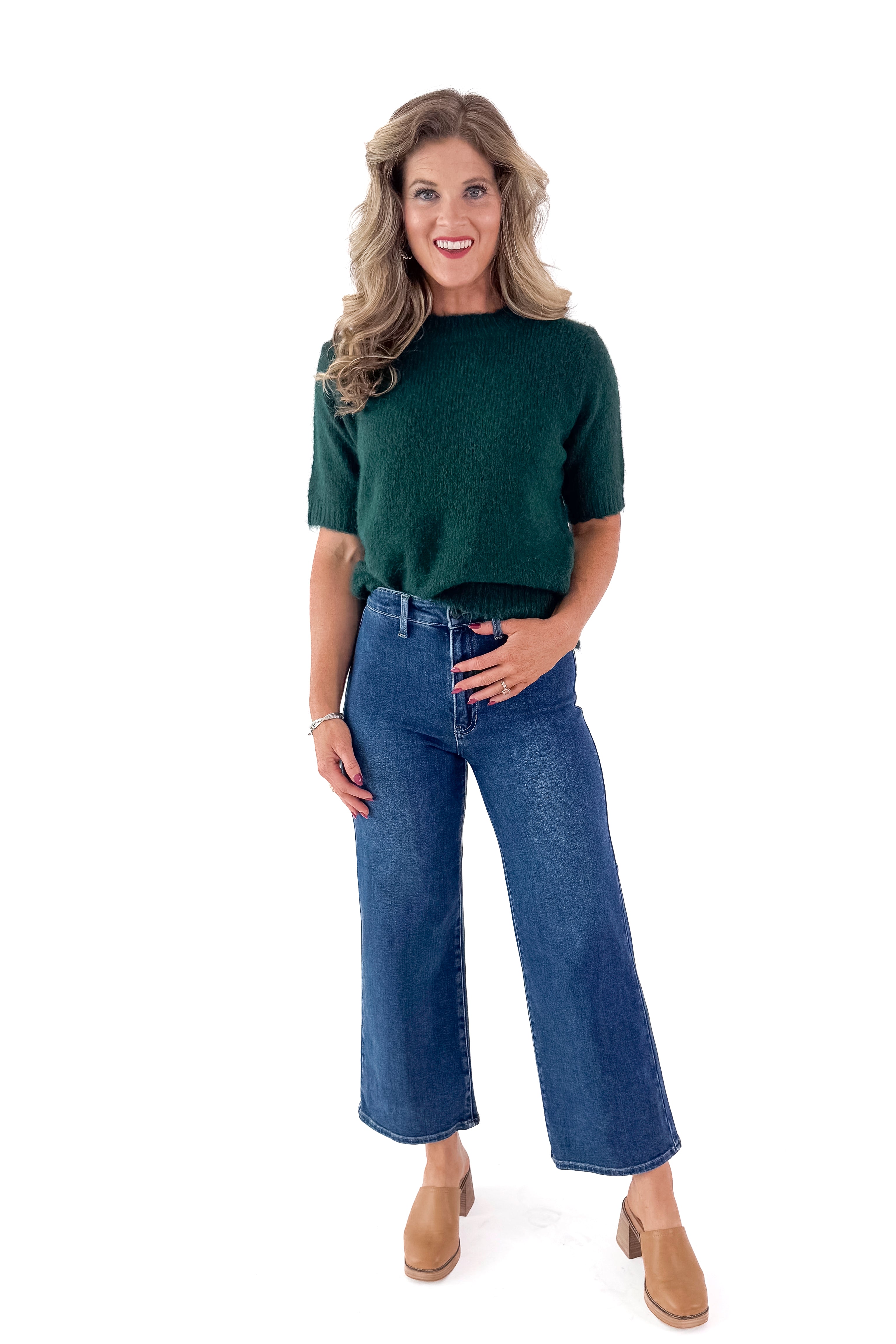 Front view of woman wearing green sweater with Dark Wash No Pocket Trouser Jeans against white studio background.