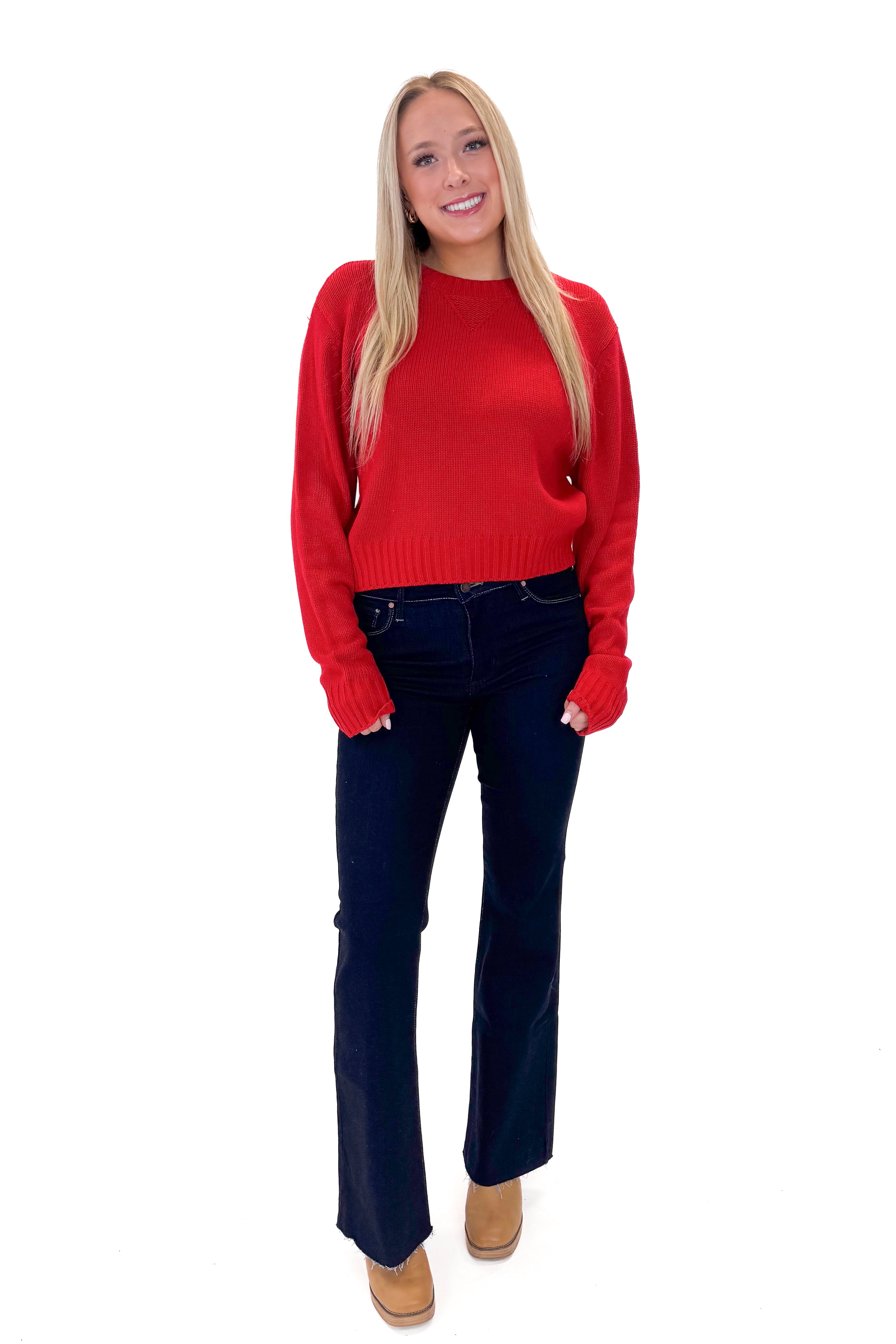 Front view of woman wearing Red Ribbed Neck Sweater with jeans against white studio background.