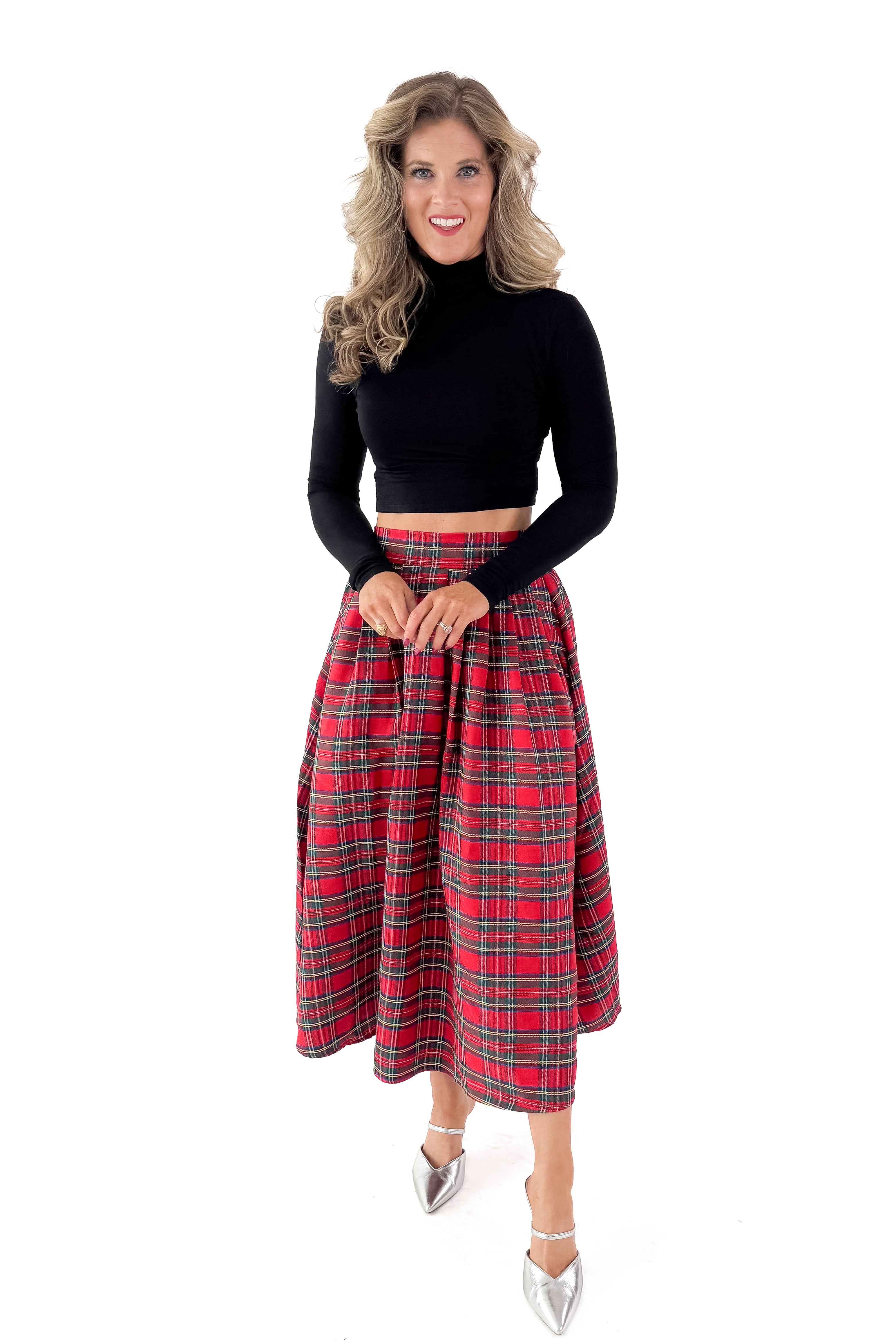 Front view of woman wearing black top with skirt against white studio background.