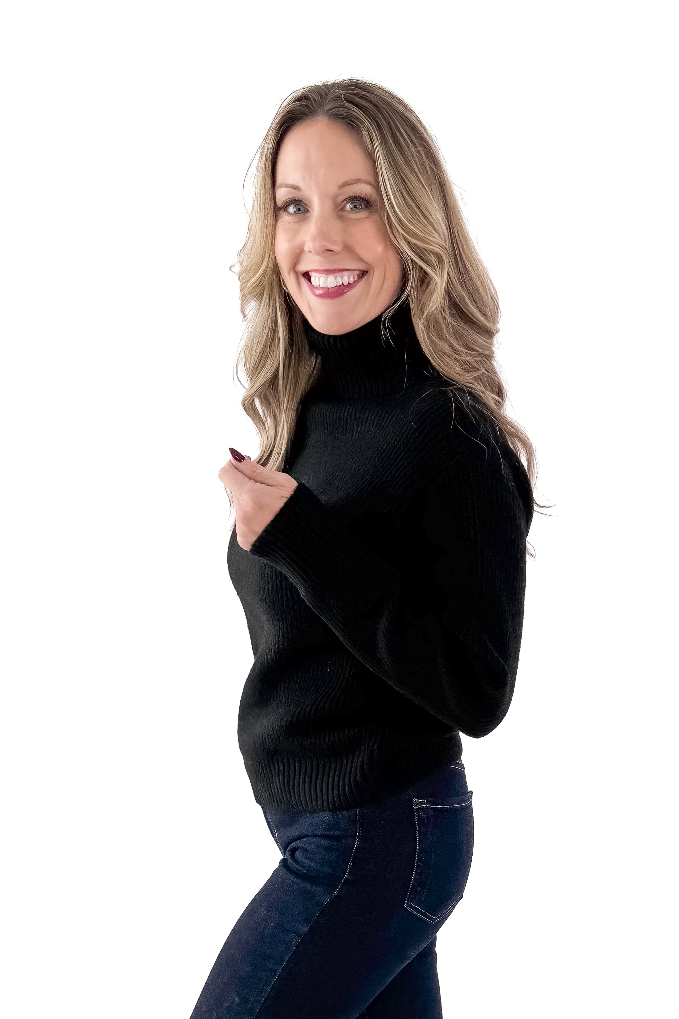 Front view of woman wearing black sweater with jeans against white studio background.