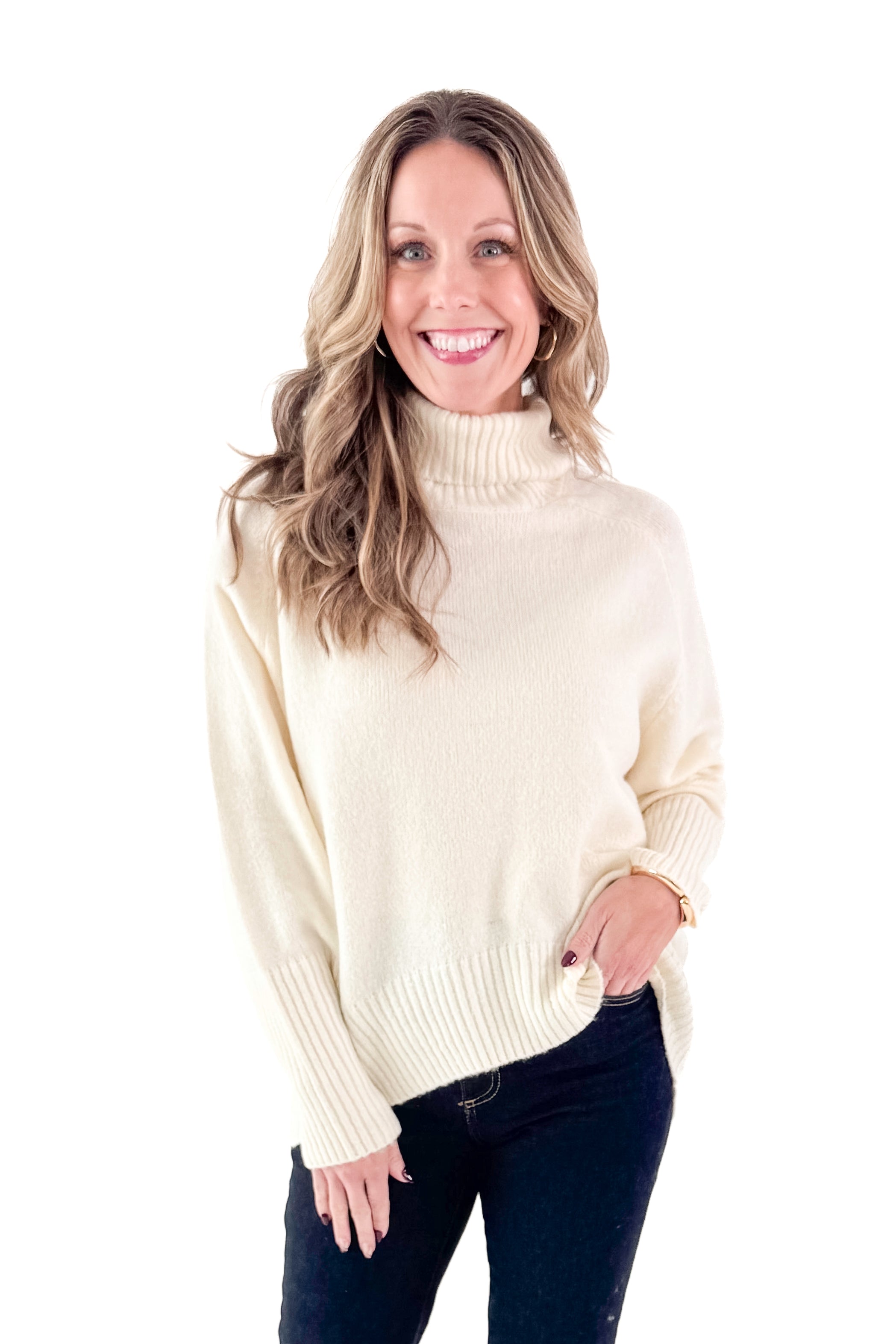Front view of woman wearing Cream Turtleneck Sweater with jeans against white studio background.