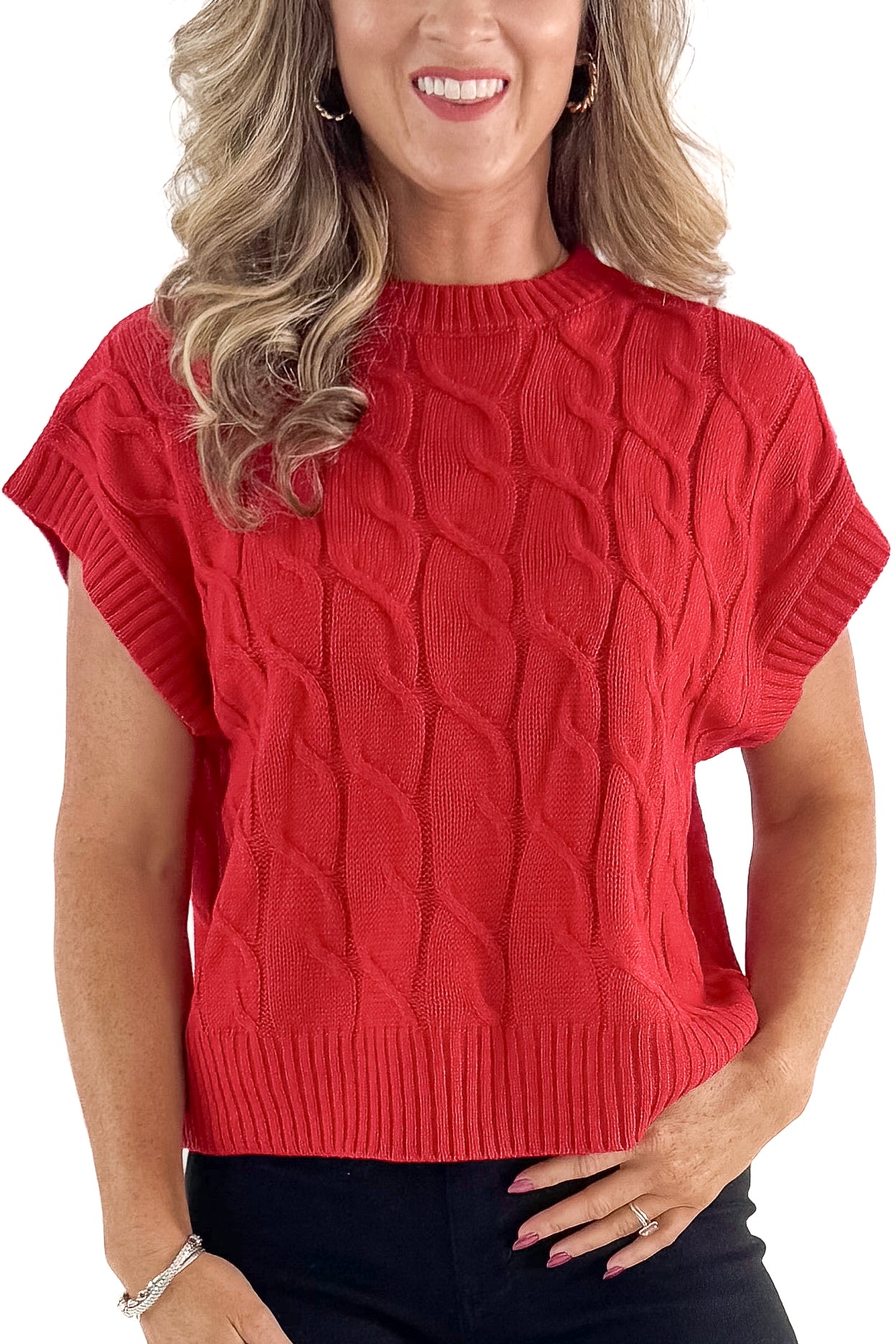 Front detailed view of woman wearing red sleeveless sweater with jeans against white studio background.