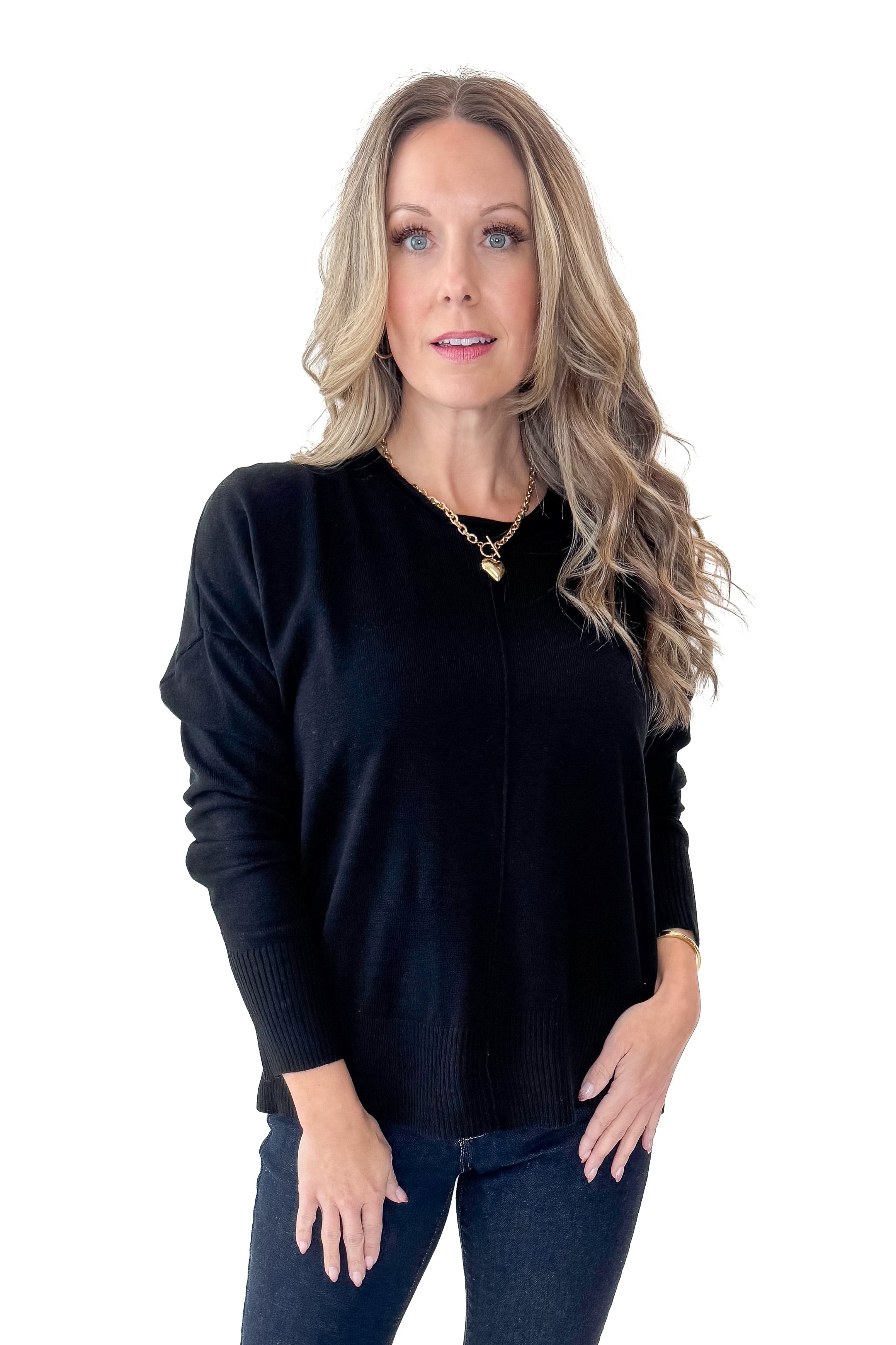 Front view of woman wearing Black Center Seam Round Neck Sweater with jeans against white studio background.