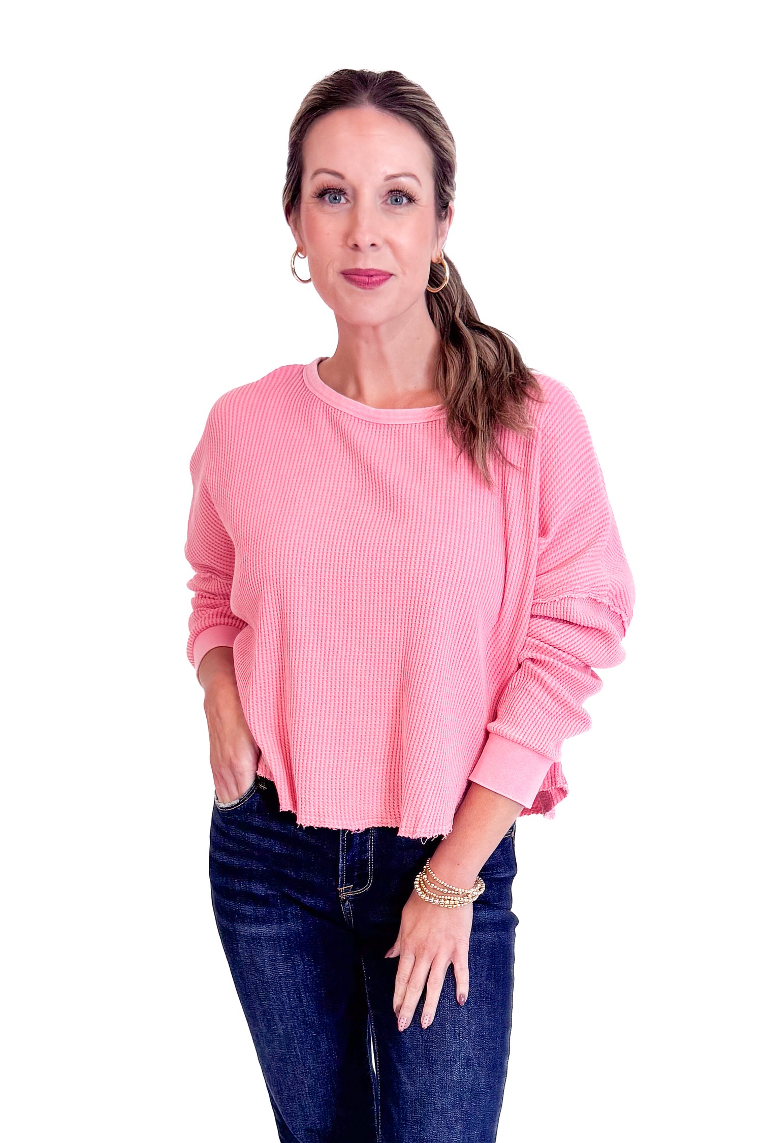 Woman wearing a pink sweater and blue jeans on a white background