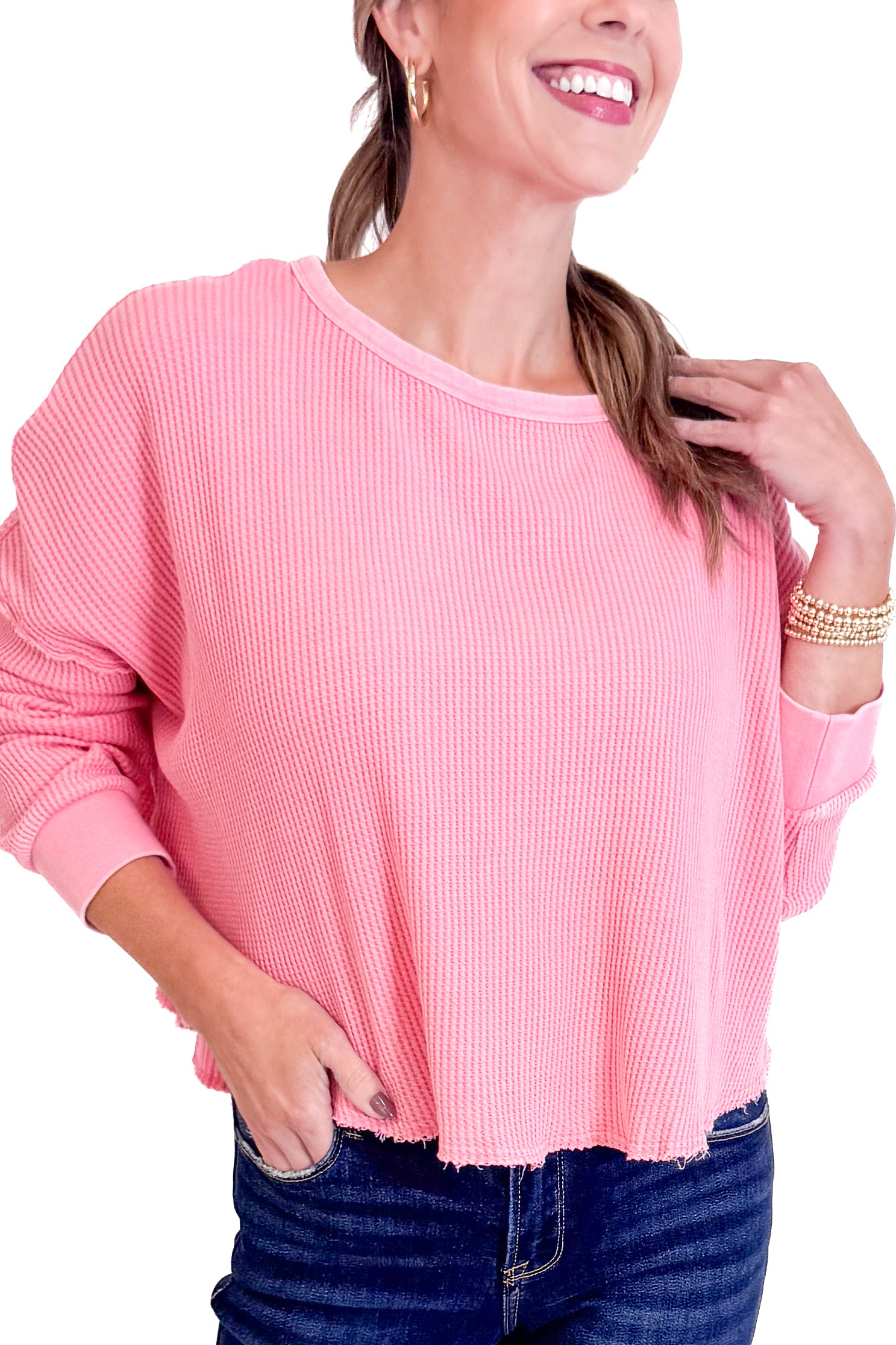 Woman wearing a pink sweater and blue jeans on a white background