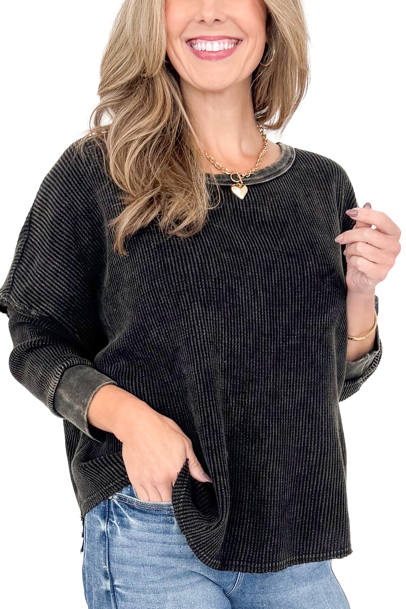 Front detailed view of woman wearing washed black waffle top with jeans against white studio background.