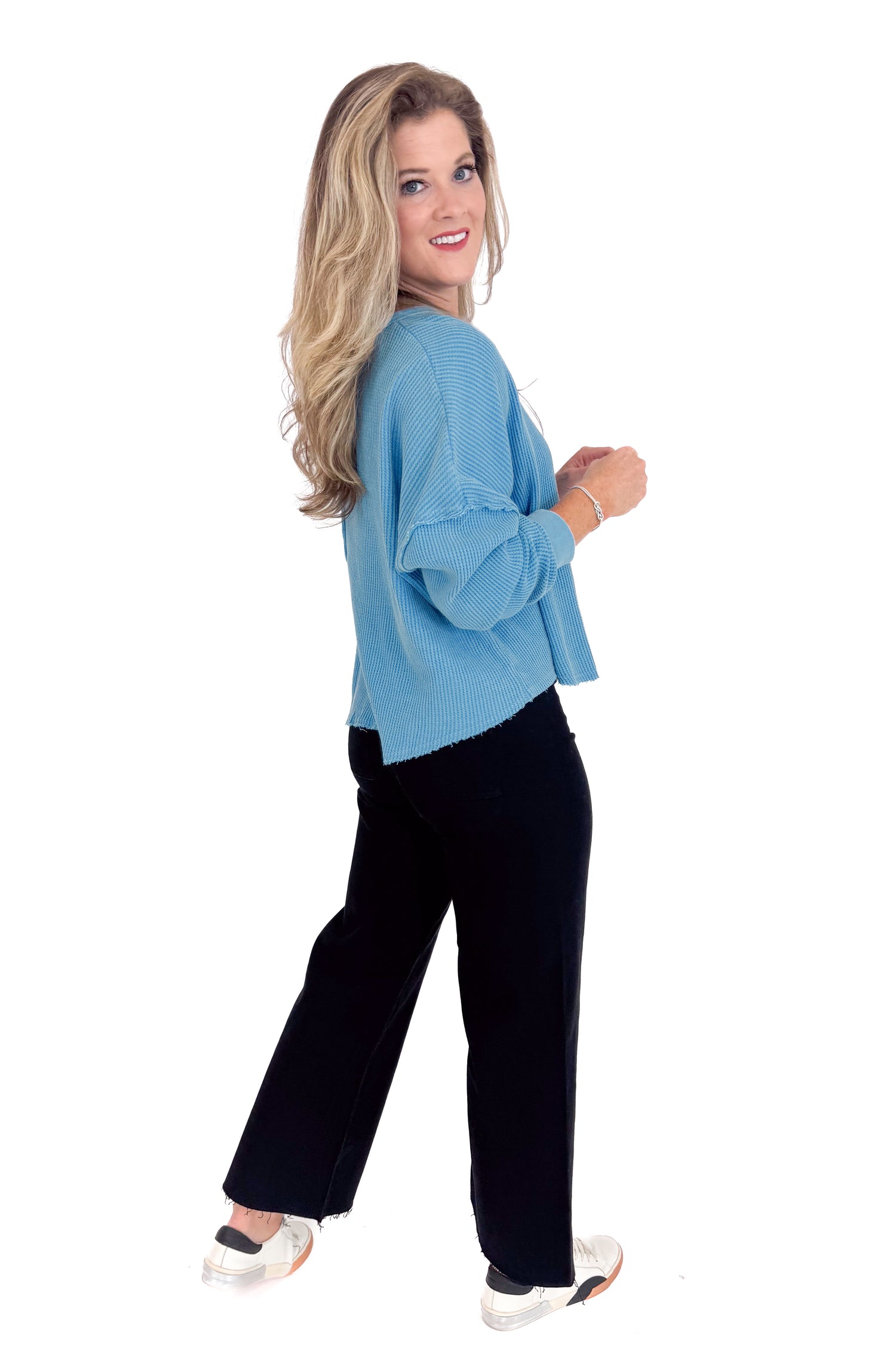Woman wearing a blue top and black pants on a white background