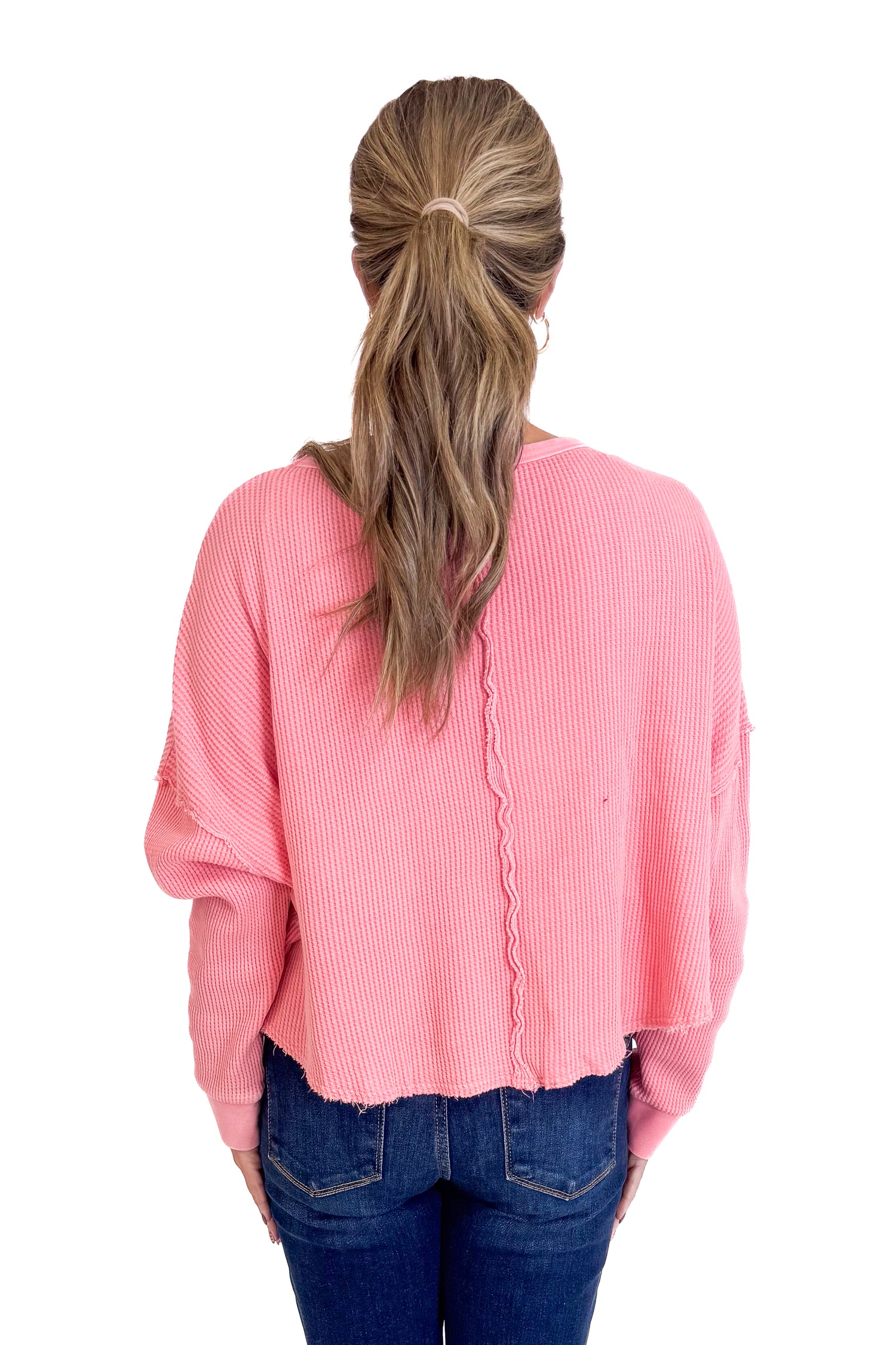 Person wearing a pink sweater with a white background